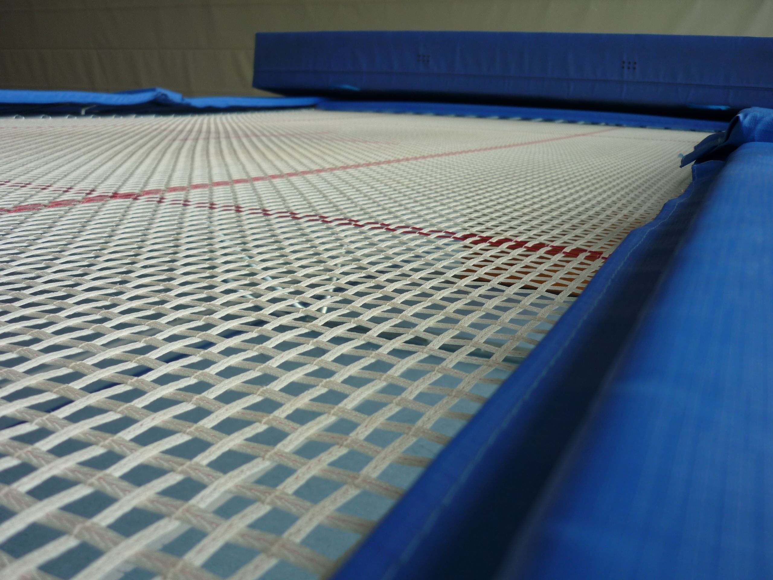 Trampoline gymnastics: A sports device consisting of a piece of taut, strong fabric stretched between a steel frame using many coiled springs. 2560x1920 HD Background.