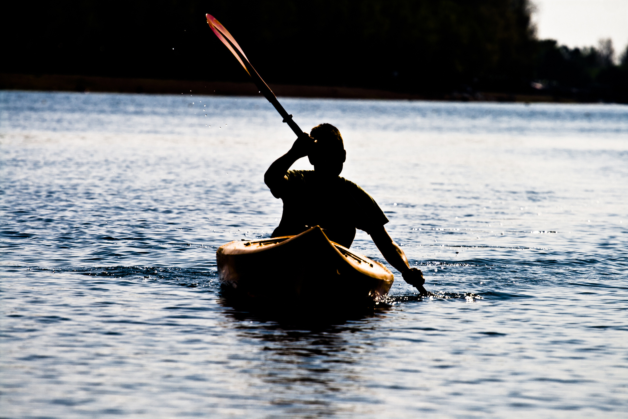 Canoeing: Man uses a double-bladed paddle to move over the water in his kayak. 2130x1420 HD Background.