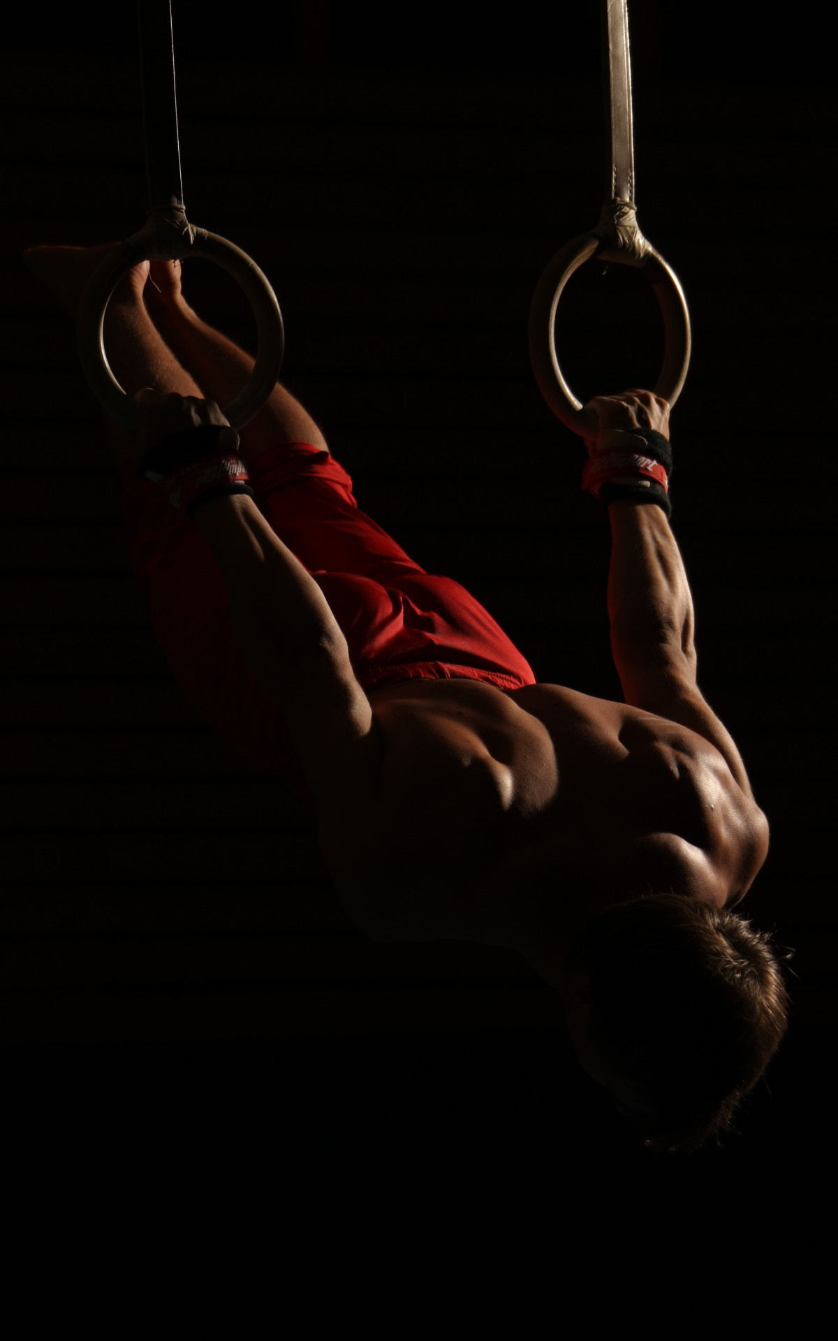 Acrobatic Gymnastics: A gymnast uses still rings - an artistic event apparatus that requires extreme upper body strength. 1200x1920 HD Background.