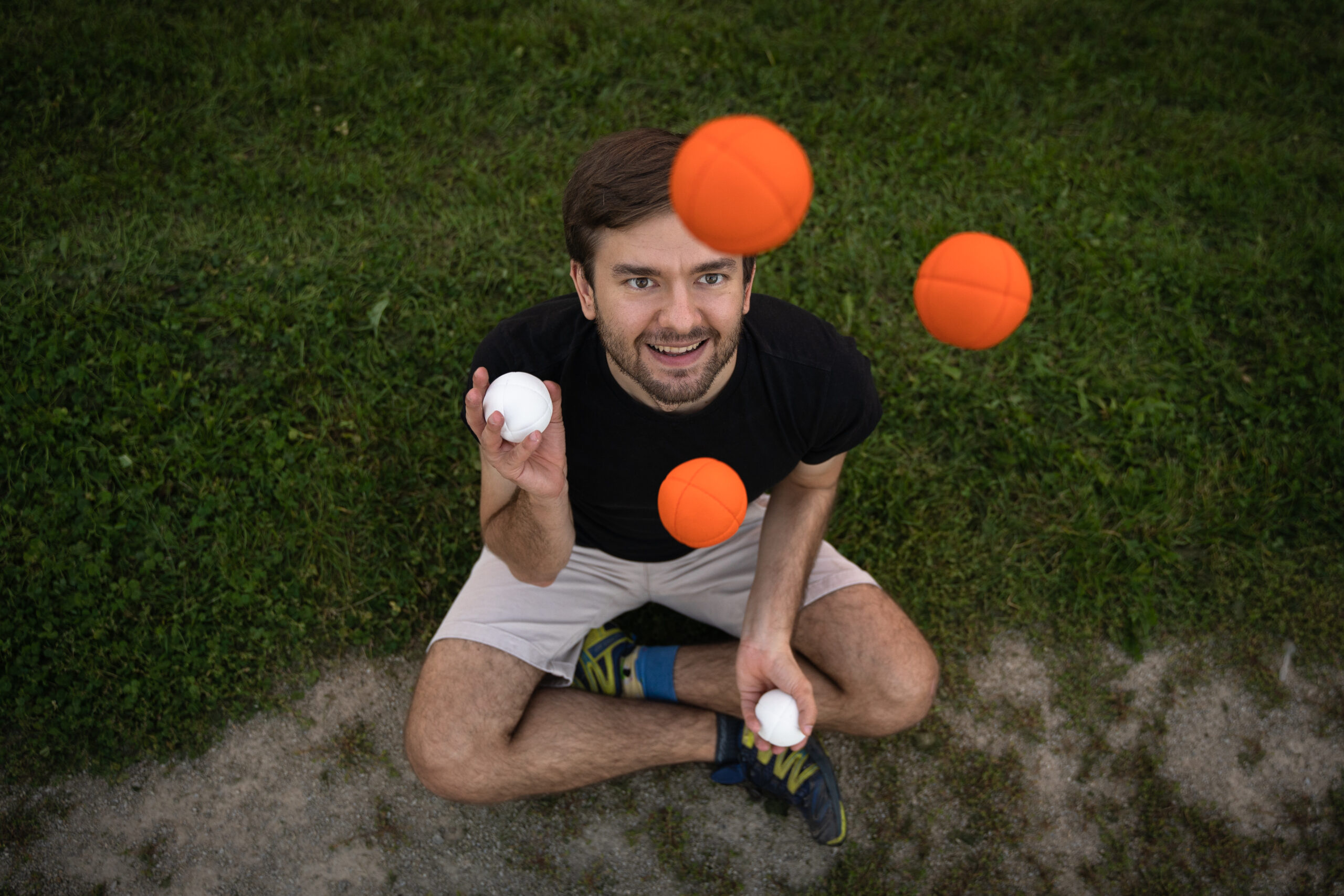 Juggling: An amateur performance by a juggler with white and orange balls serving as props. 2560x1710 HD Background.