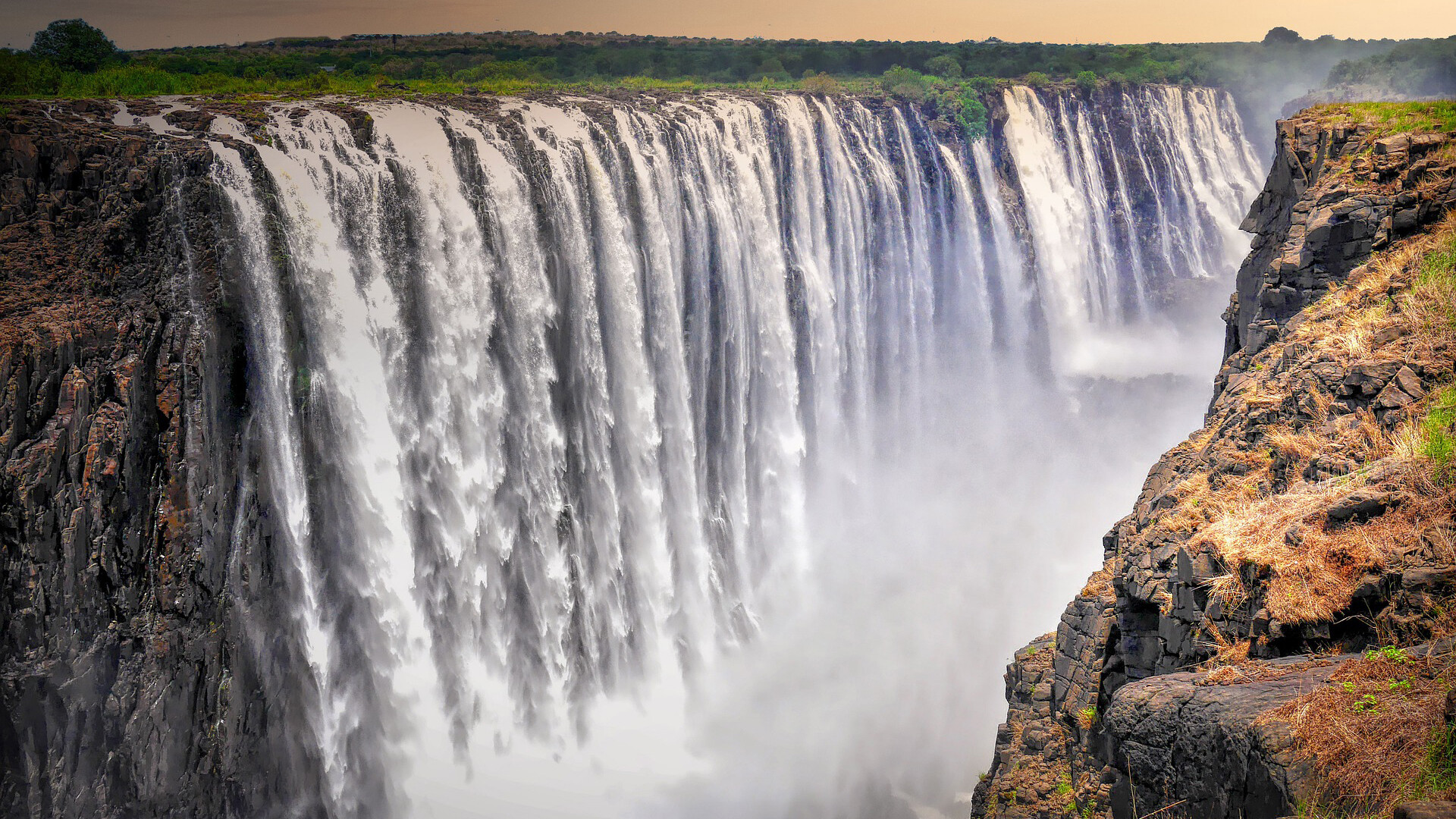 Victoria Falls: Mosi-Oa-Tunya, Zambezi river plunging into a narrow gorge of over 100 meters deep. 1920x1080 Full HD Background.