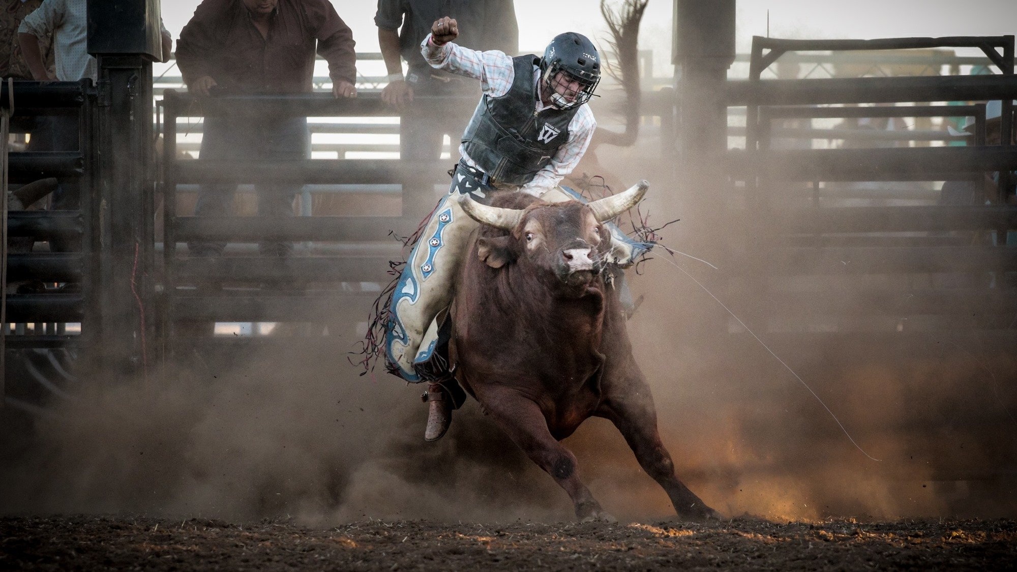 Bullriding: Bullring, Helmet, Cowboy, A rodeo event in which the contestant attempts to ride a bucking bull. 2000x1130 HD Background.