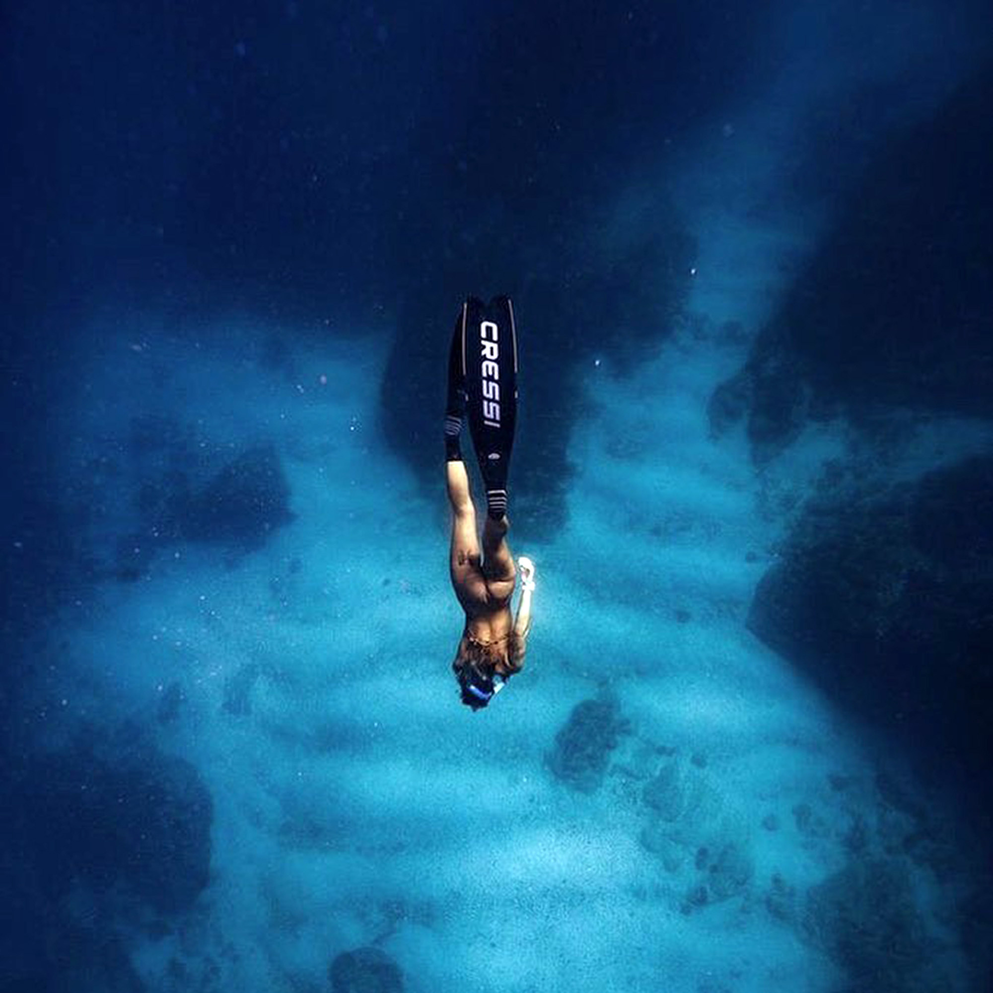Freediving: A female skin diver explores the sea depths without a scuba set. 2000x2000 HD Background.