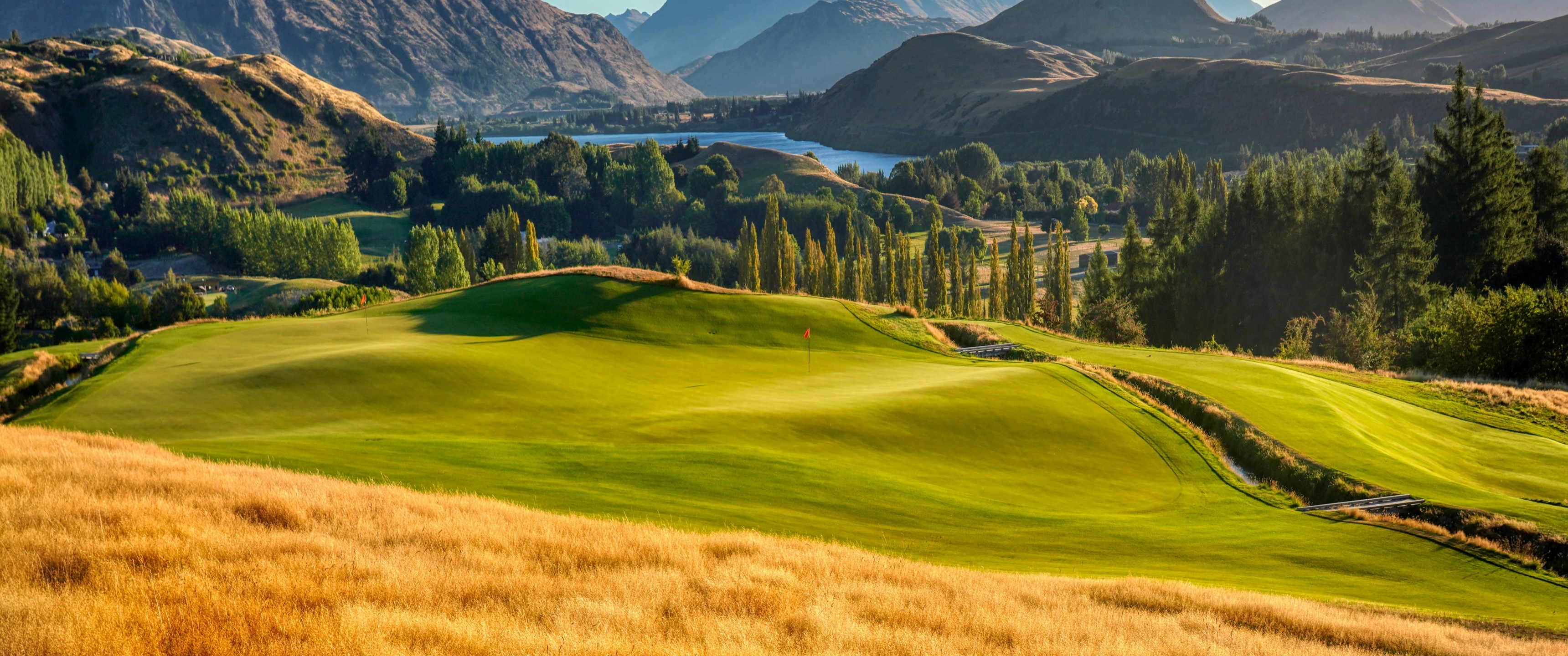 Golf Course: Landscape, Mountains, Lake, Par 3, Green, Nature, Eagle, Kikuyu, Grass, Trees. 3440x1440 Dual Screen Wallpaper.