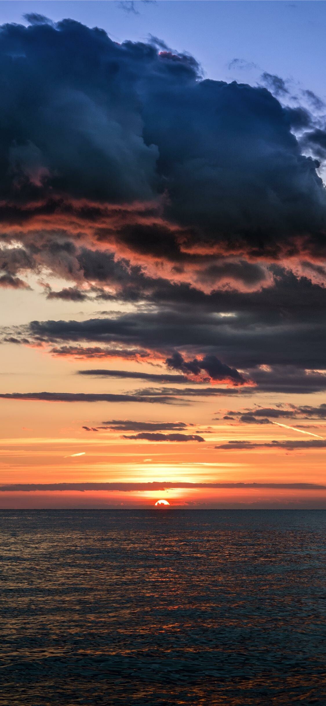 Sunset: Sundown, The sun breaking through a dark-bottomed cloud. 1130x2440 HD Background.