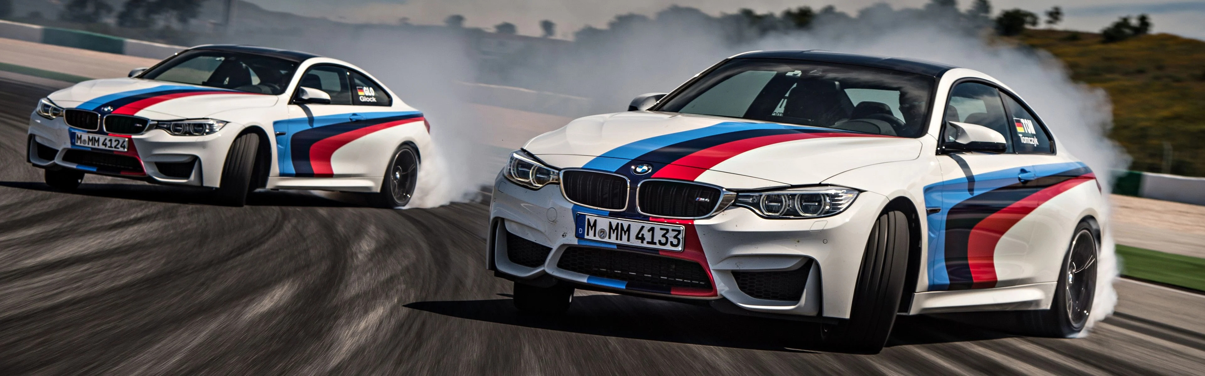 Drifting: BMW M4 F82 high-performance sports cars, Extreme turn, Racing track. 3840x1200 Dual Screen Background.
