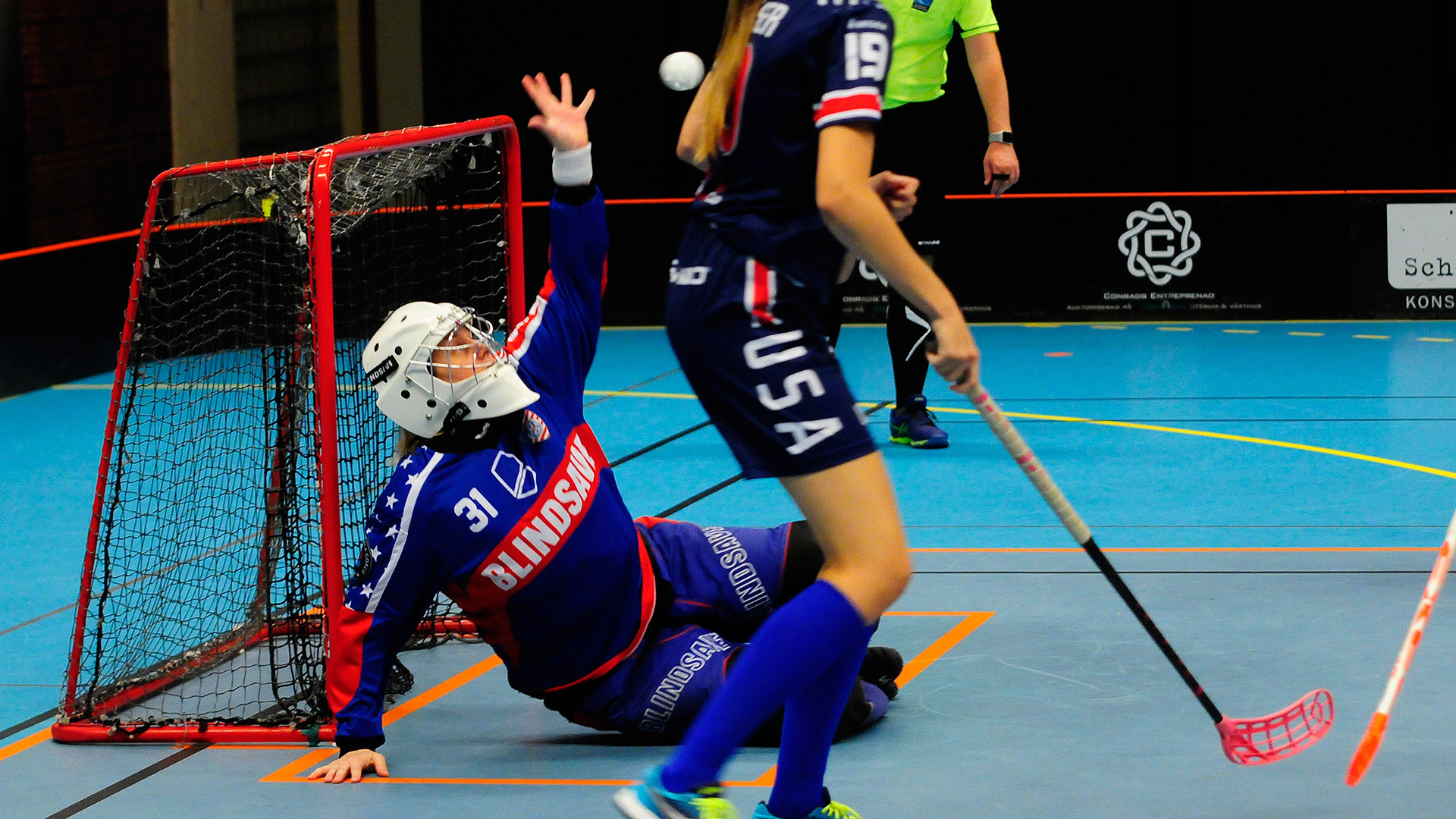 Floorball: The US National women's team goalkeeper catches the ball at the competition. 1920x1080 Full HD Background.