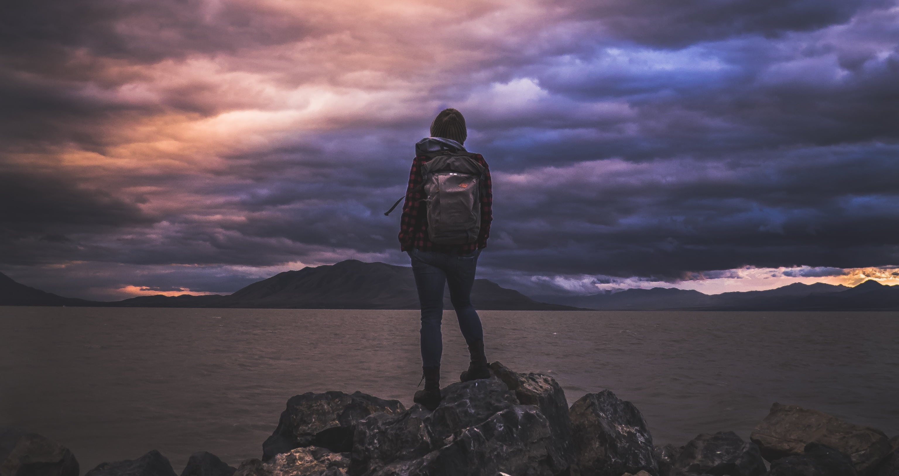 Backpacking: Girl stands on the rocks near the lake during the golden hour, Natural landscape. 3080x1630 HD Background.