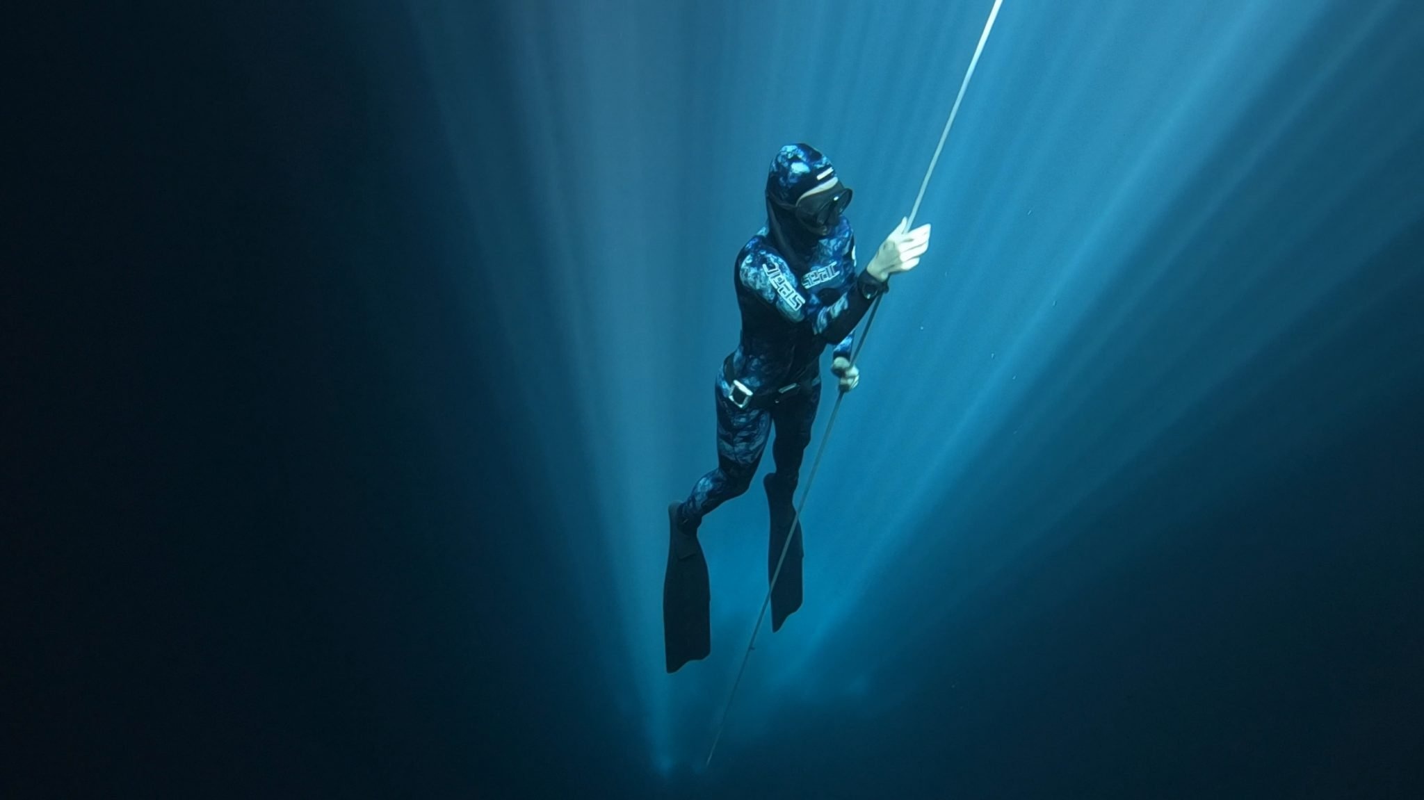 Freediving: A diver equipped with flippers and a diving mask during the ascending process. 2050x1160 HD Background.