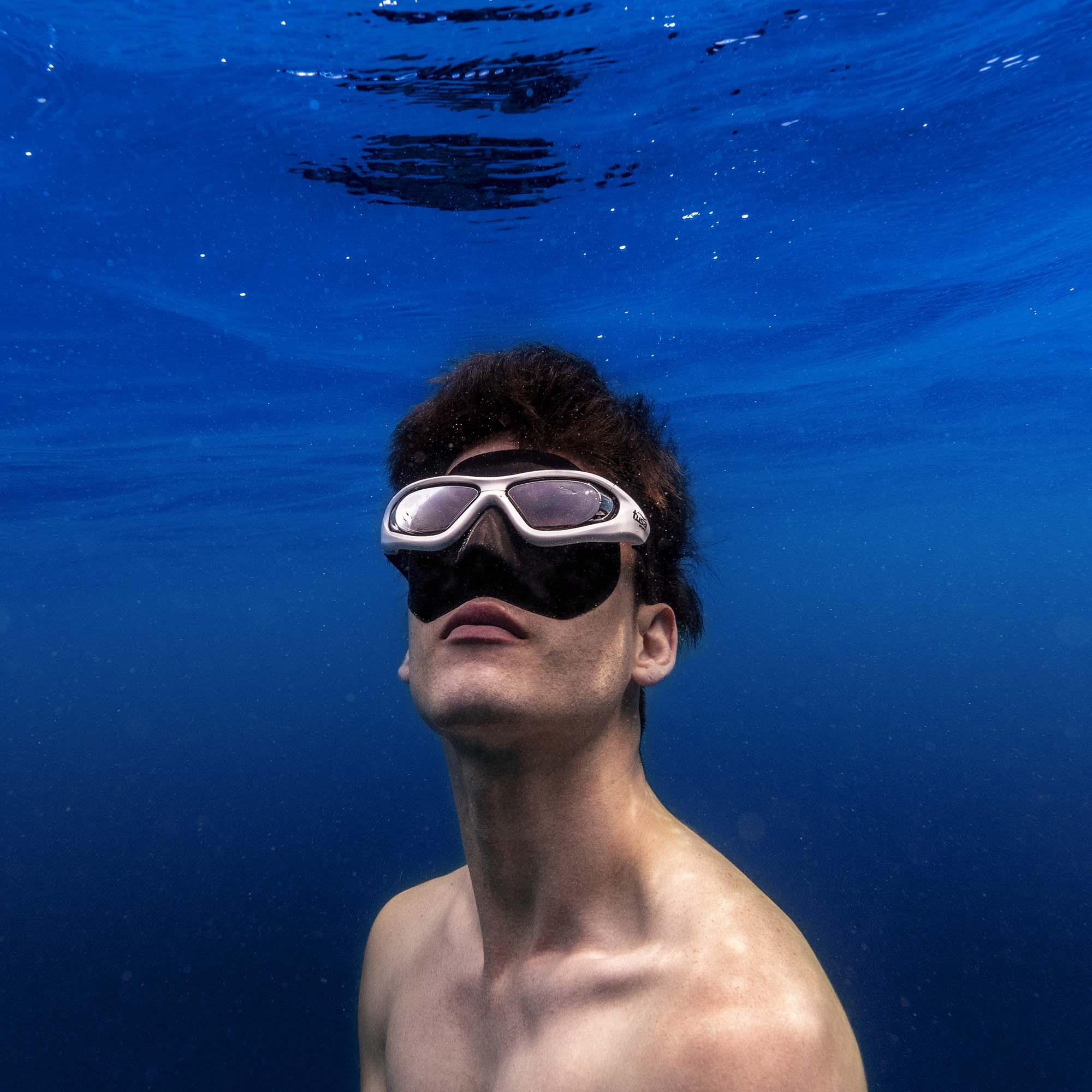 Freediving: Freediver wears a protective diving mask while being underwater. 2000x2000 HD Background.