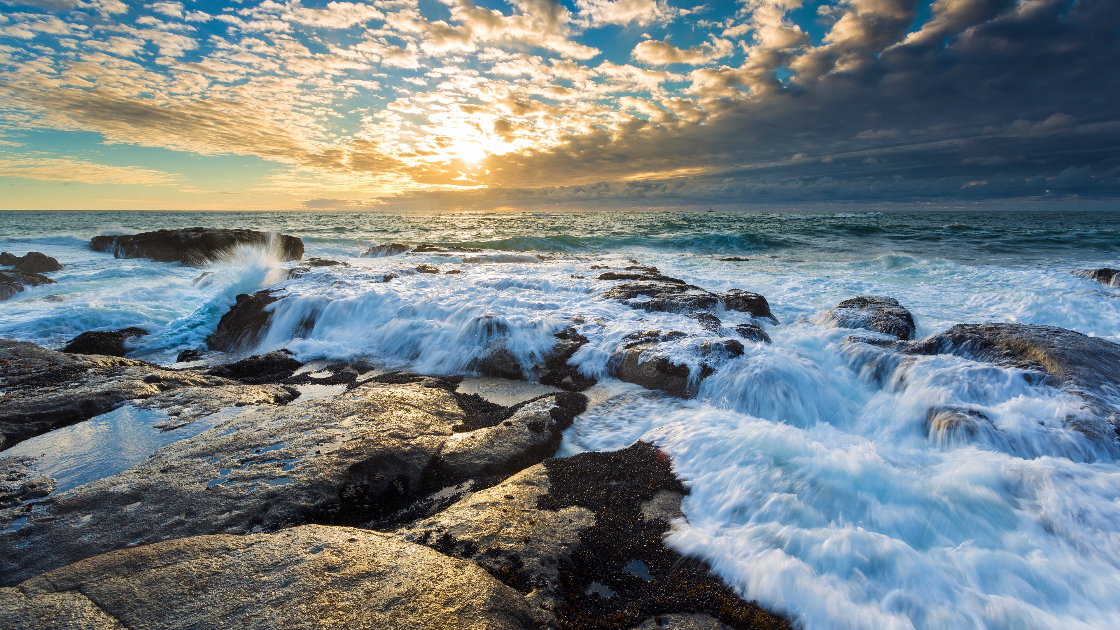 Seascape: Foamy waves attack the beach cliffs covered with moss, Cloudy sunset. 3840x2160 4K Background.