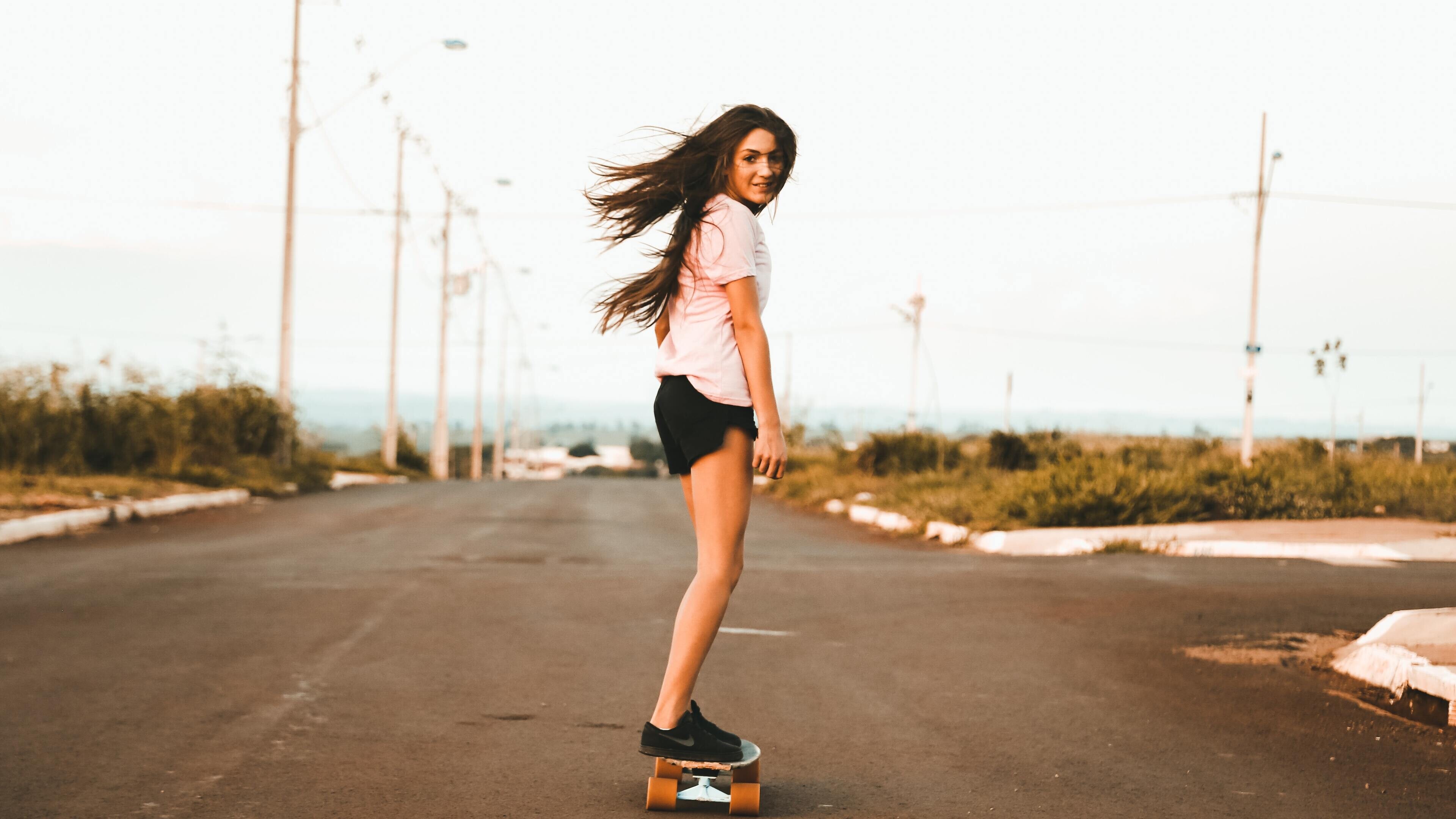 Girl Skateboarding: Longboard, Typically designed and optimized for cruising, Covering distances at moderate speeds. 3840x2160 4K Wallpaper.