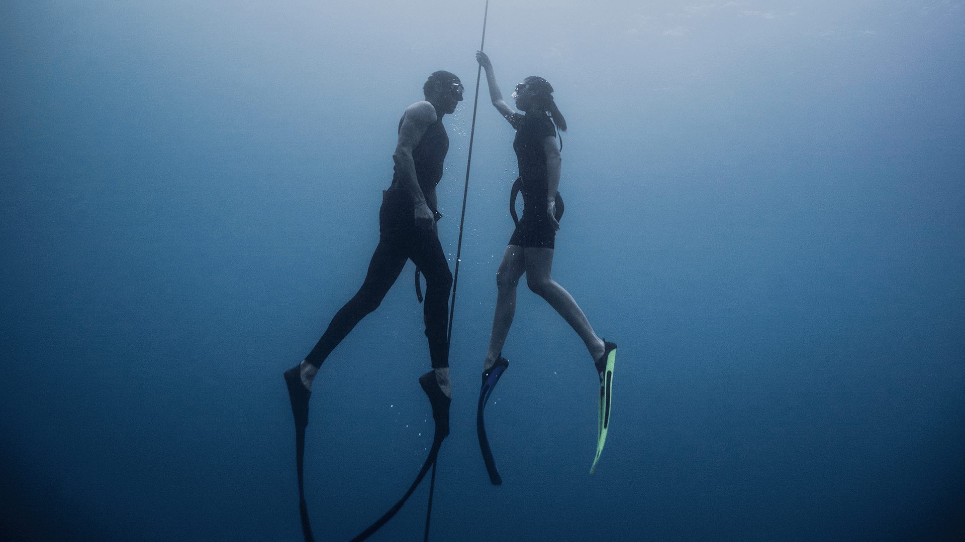 Freediving: A couple performs a slight ascending procedure, Recreational water sport. 1920x1080 Full HD Background.