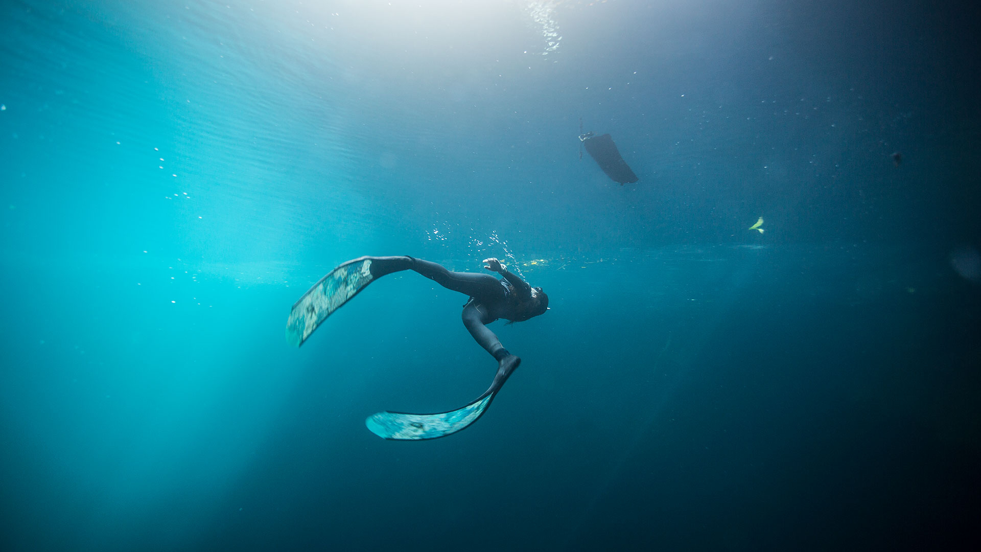 Freediving: Underwater swimming performed by a breath-hold diver equipped with flippers. 1920x1080 Full HD Background.