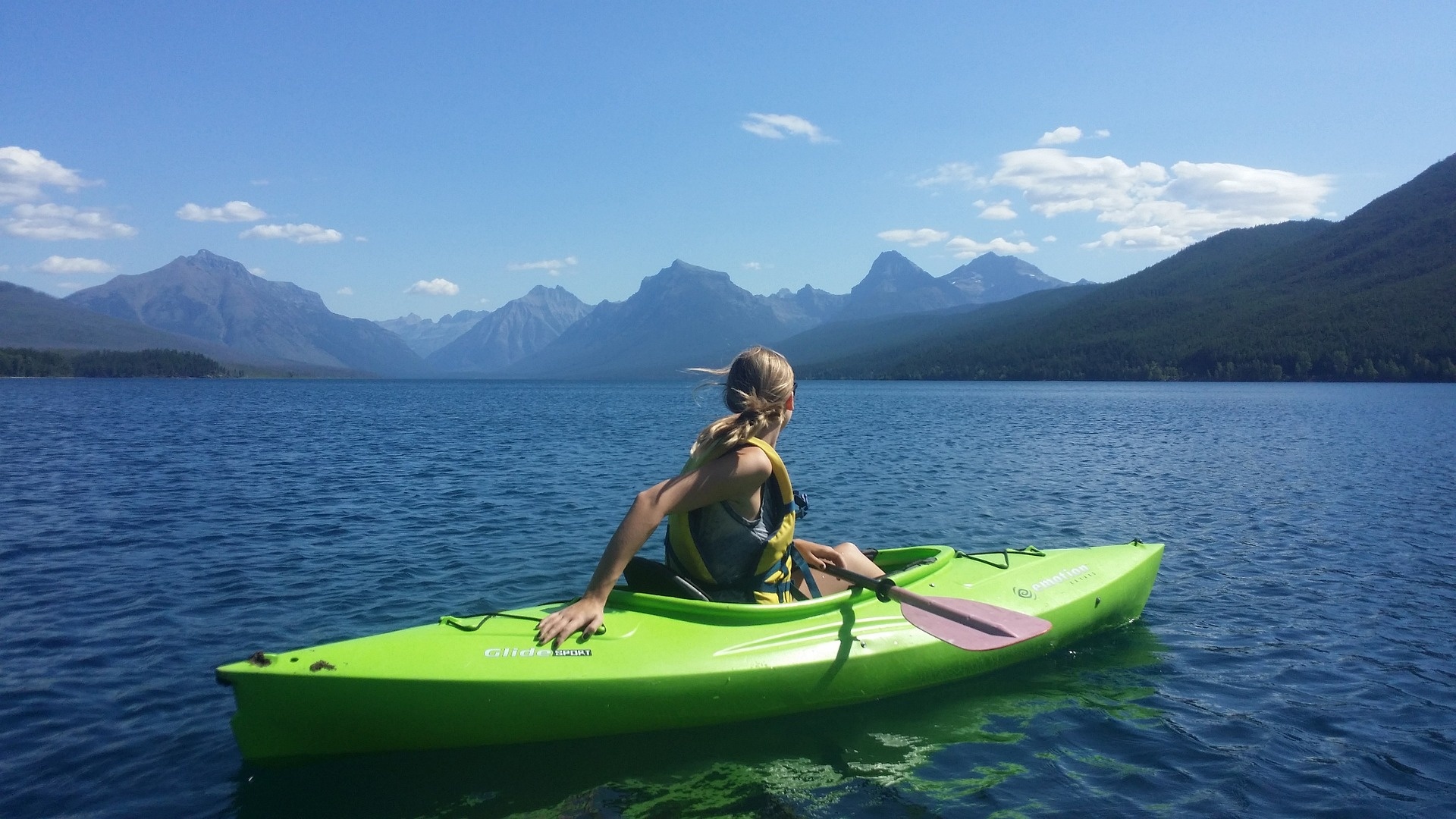 Kayaking: The female kayaker looks at the majestic mountains, Recreational water trip. 1920x1080 Full HD Background.