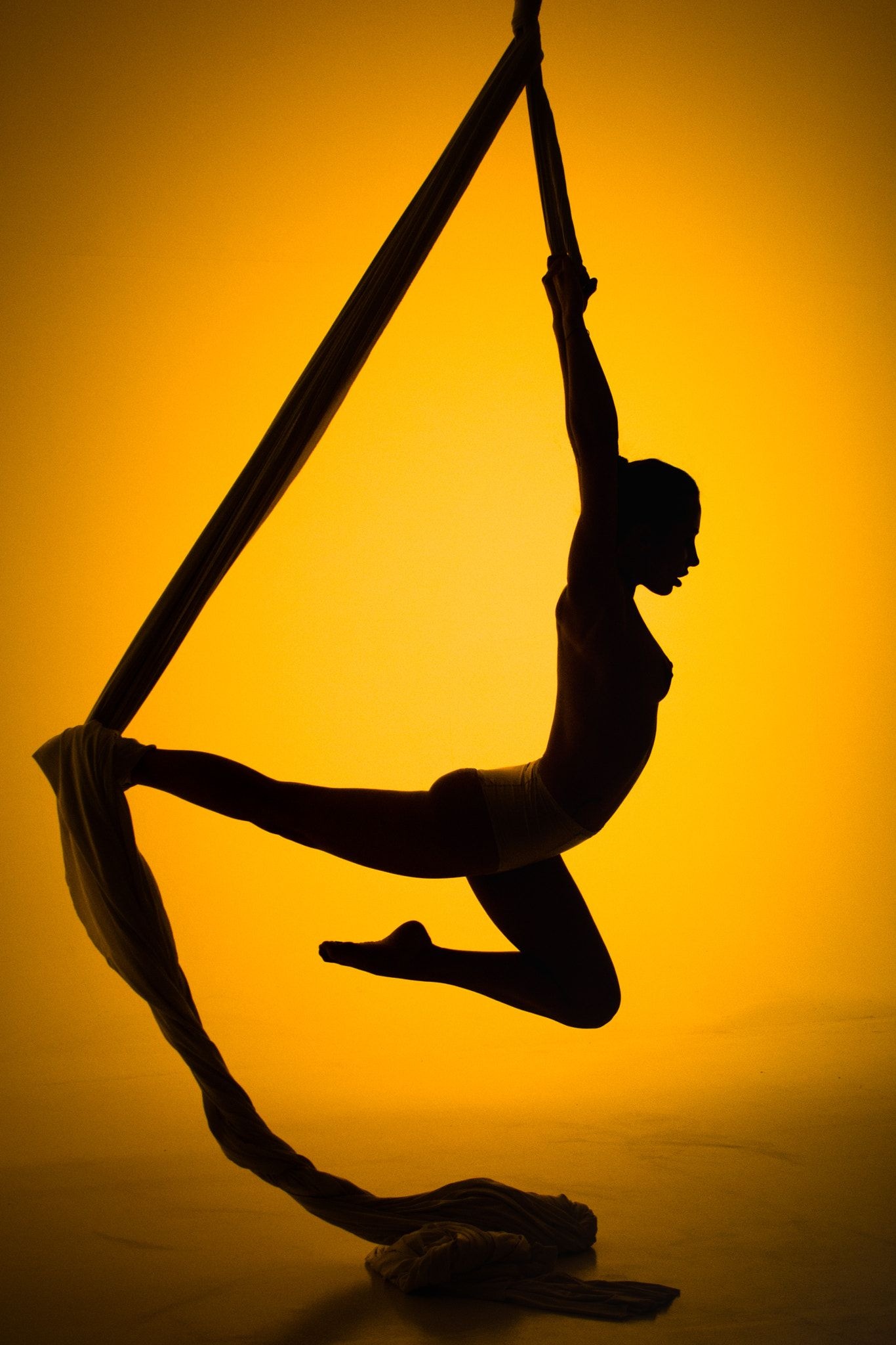 Aerial Silks: A female gymnast performs with a special ribbon while in the air. 1370x2050 HD Background.