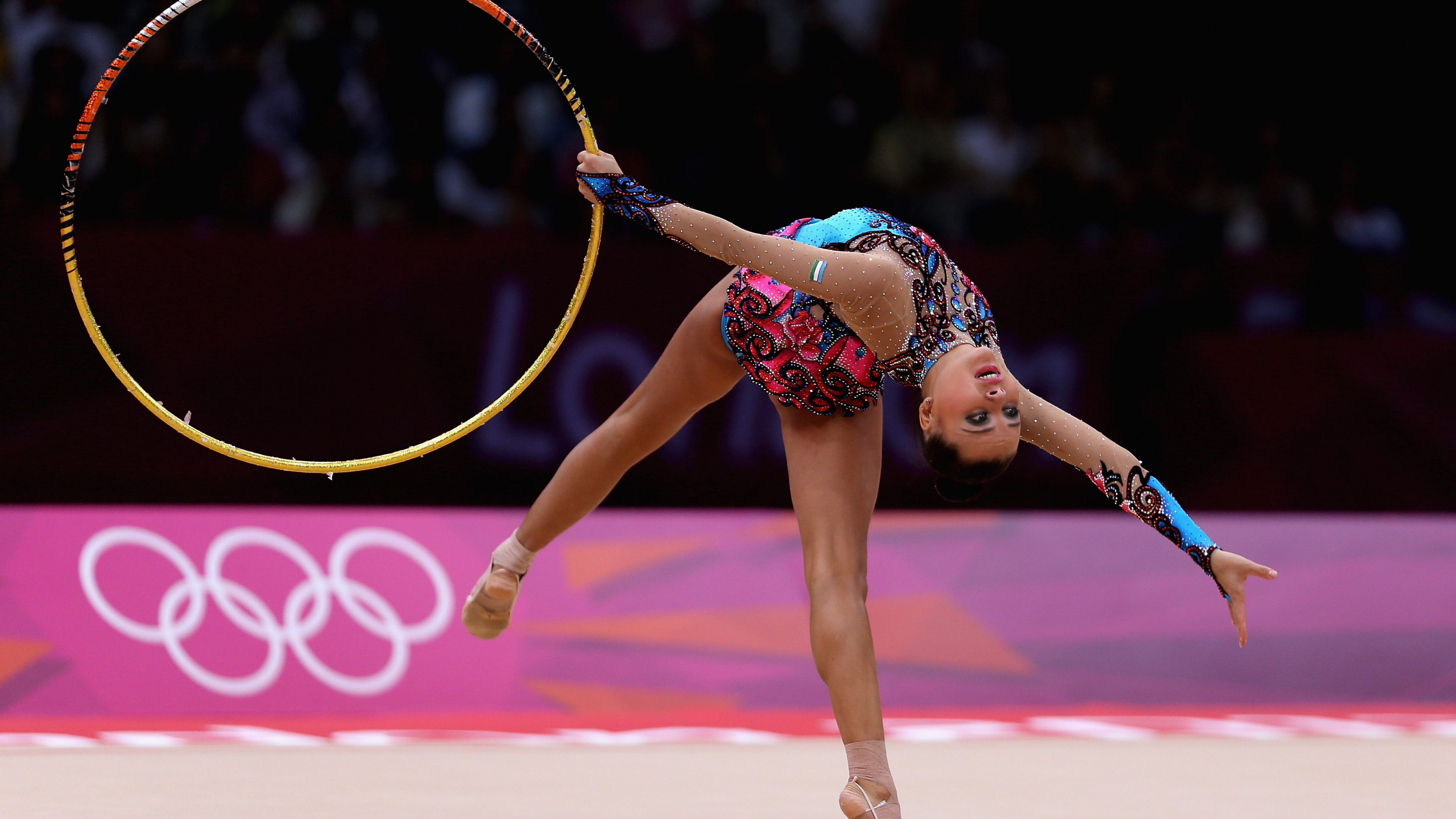 Acrobatic Gymnastics: A professional gymnast performs with a hoop at the Olympic Games. 3840x2160 4K Background.
