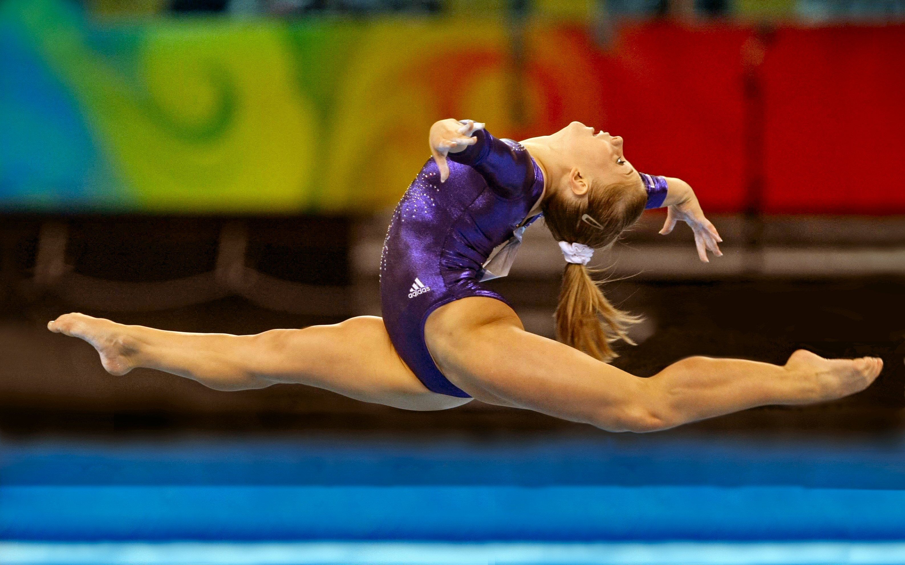 Acrobatic Gymnastics: A stretch during a jump performed by a professional floor gymnast. 3180x1990 HD Background.
