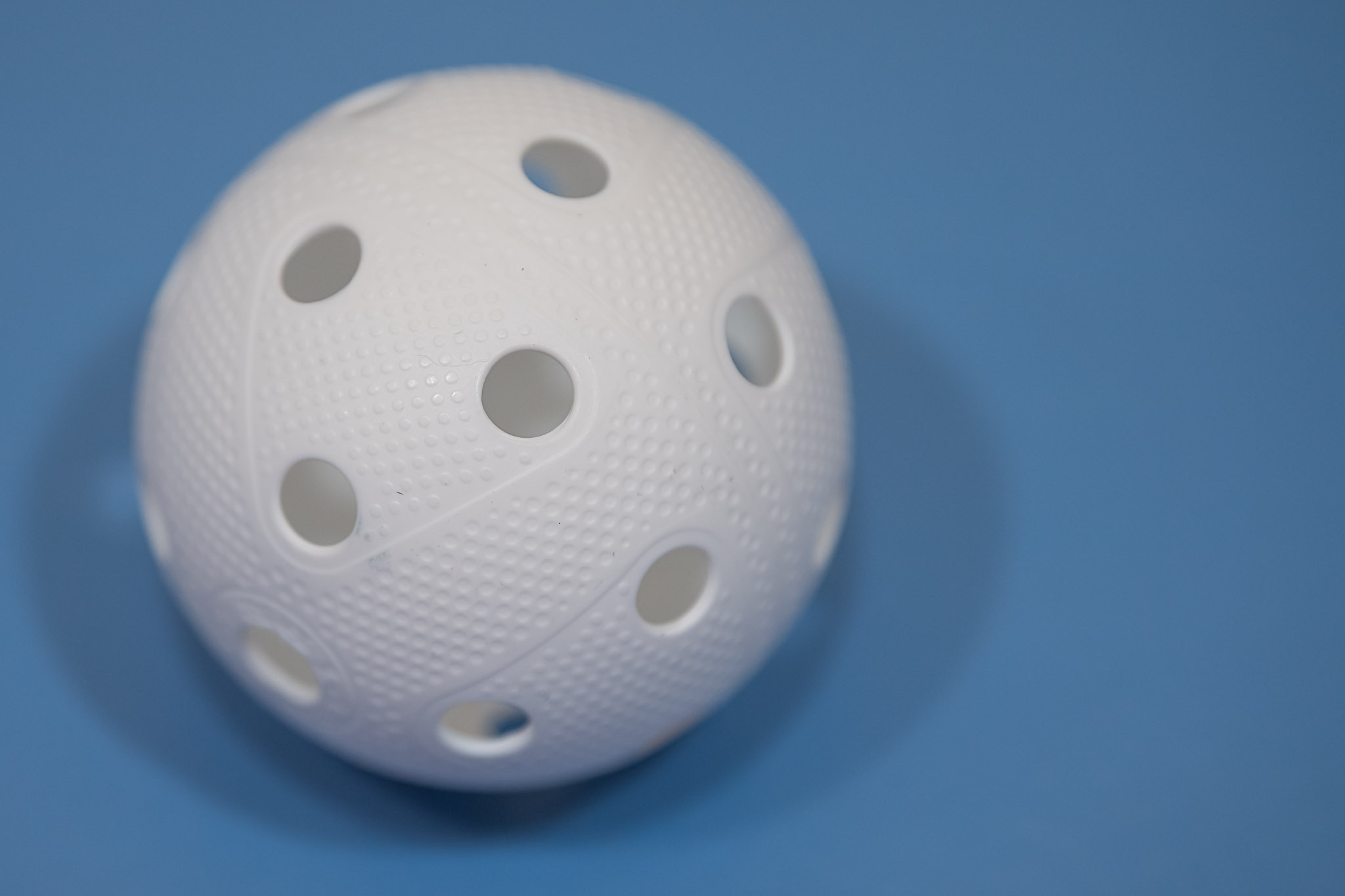 Floorball: A standard game ball that has 26 holes in it and is made with aerodynamic technology. 2050x1370 HD Background.