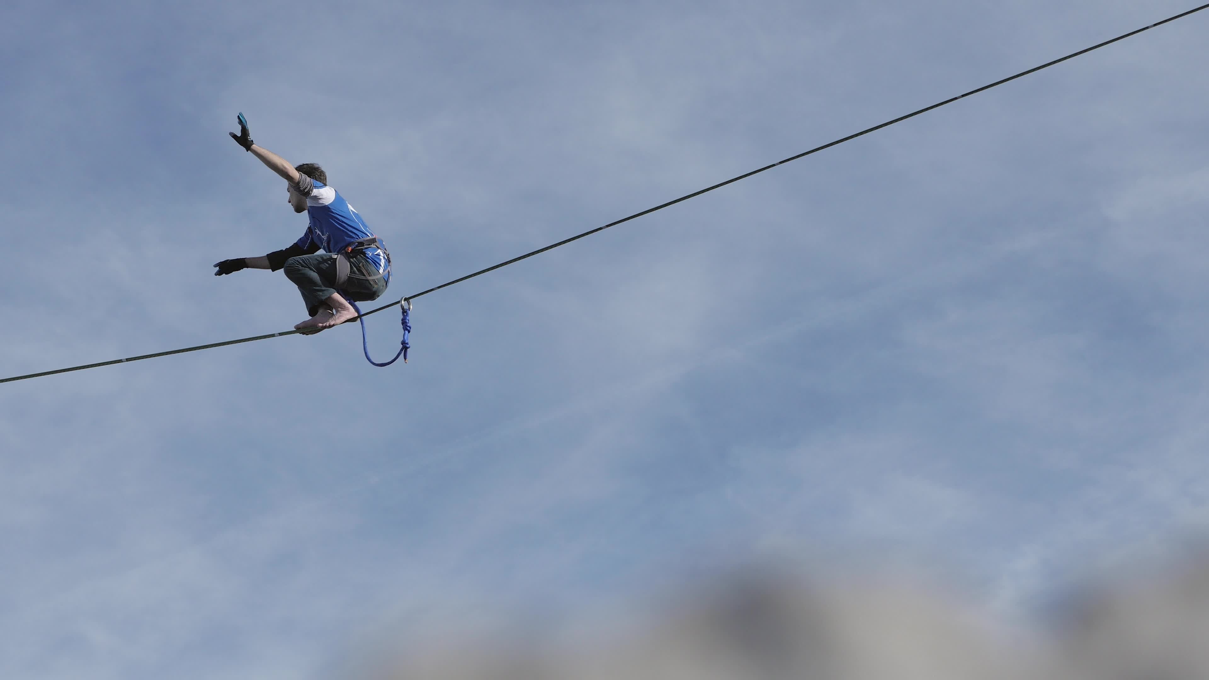 Slacklining: Walking on a rope at a high altitude, Highlining, Balancing while slacklining on a tightrope in the mountains. 3840x2160 4K Background.
