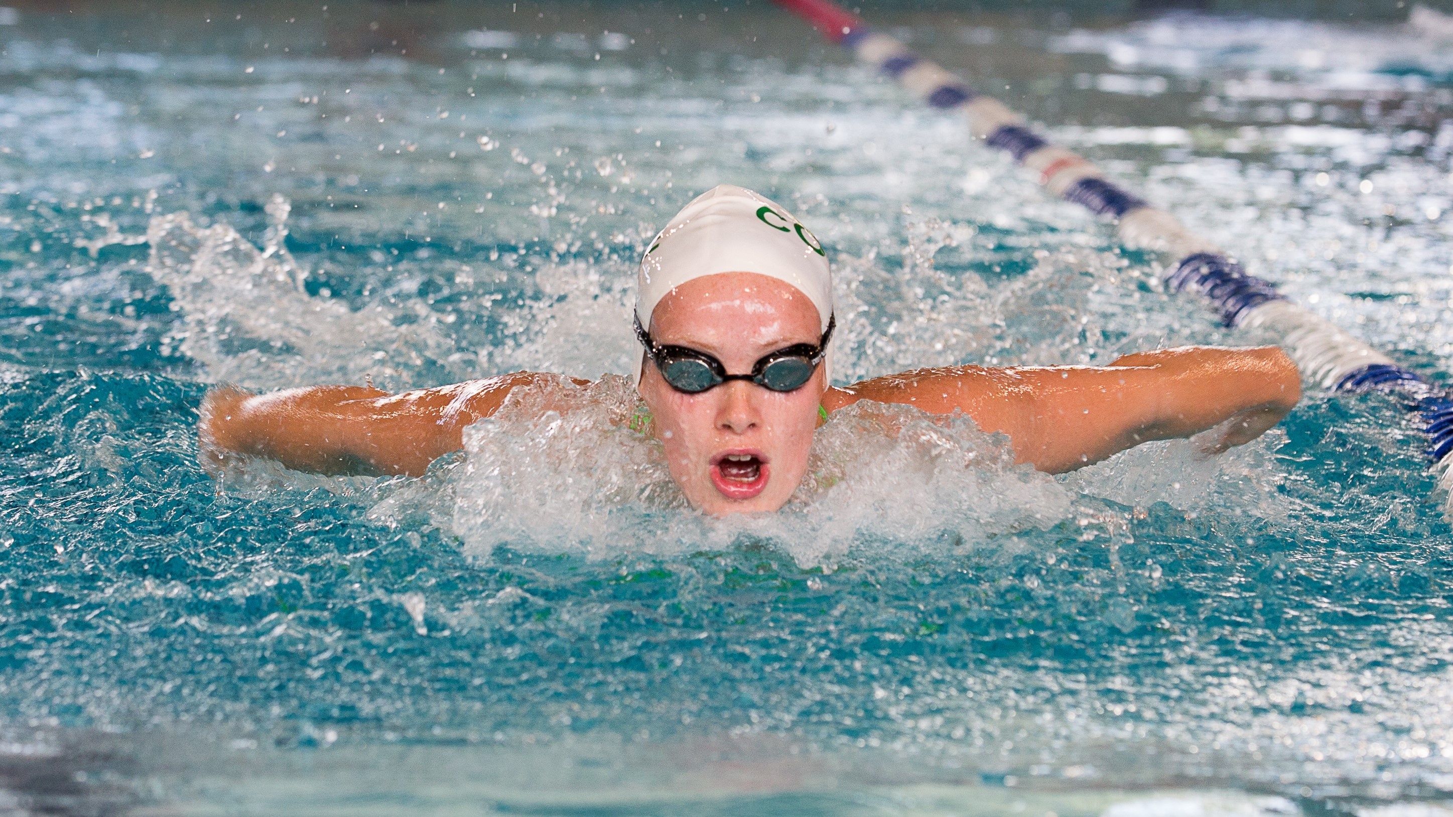 Swimming: Girl performs a butterfly stroke during the training session in the college. 2900x1630 HD Background.