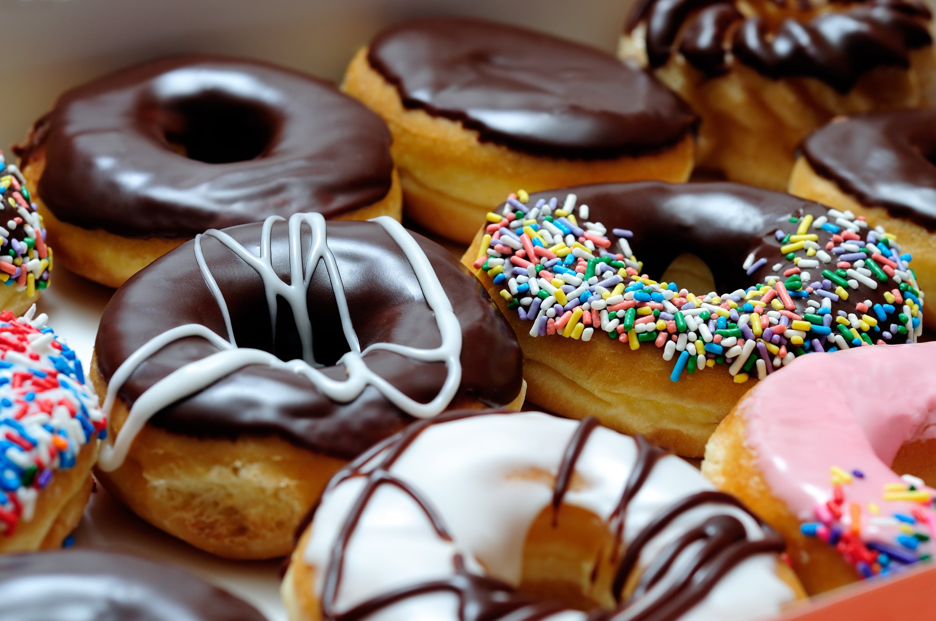 Donut: Glazed with sugar icing, spread with icing or chocolate, or topped with powdered sugar, cinnamon, sprinkles, or fruit. 3000x2000 HD Background.