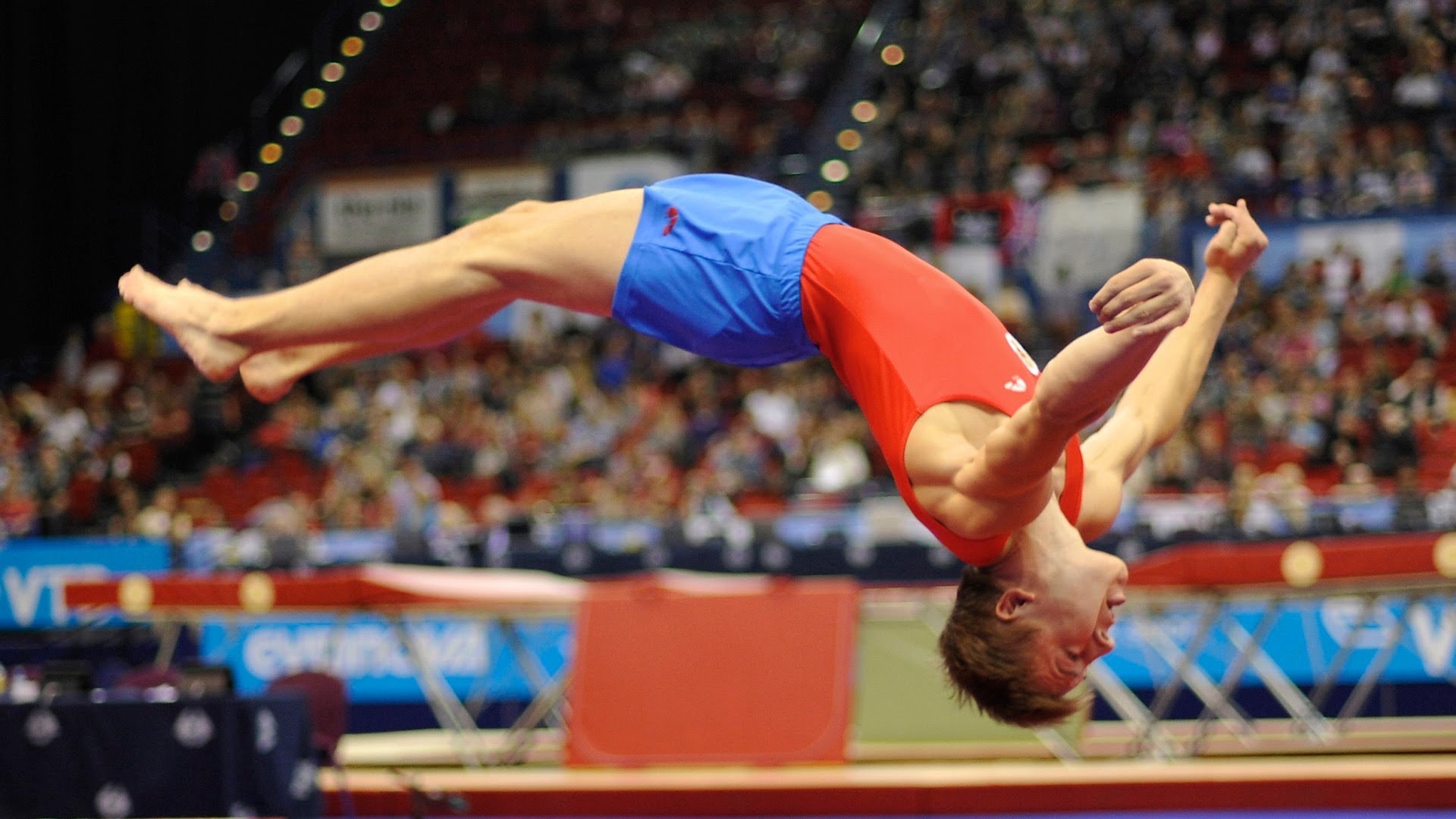Trampoline gymnastics: A back-flip trick performed by a professional gymnast, Competitive acrobatics sport discipline. 1920x1080 Full HD Background.