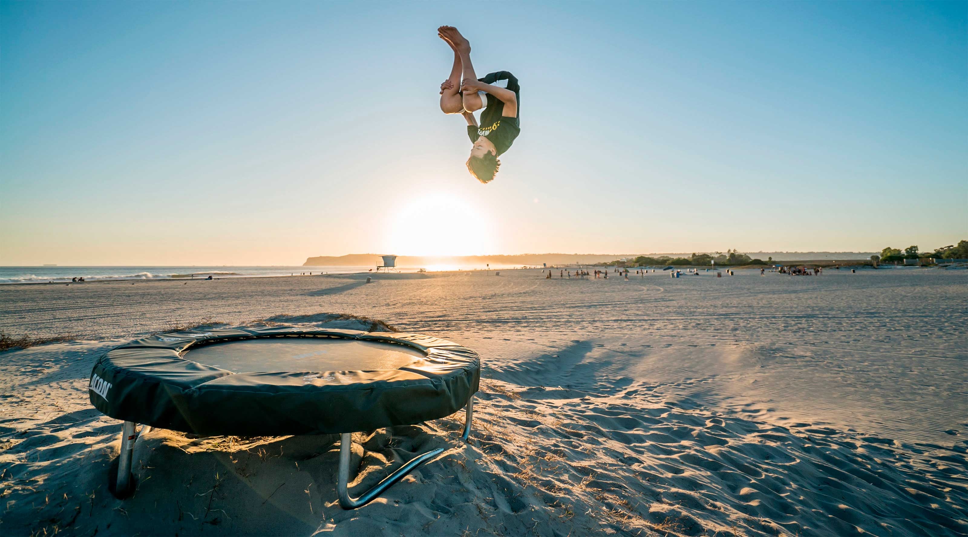 Trampolining: Recreational acrobatic activity at the beach, Forward-flip trick performed by an expert. 3200x1780 HD Background.