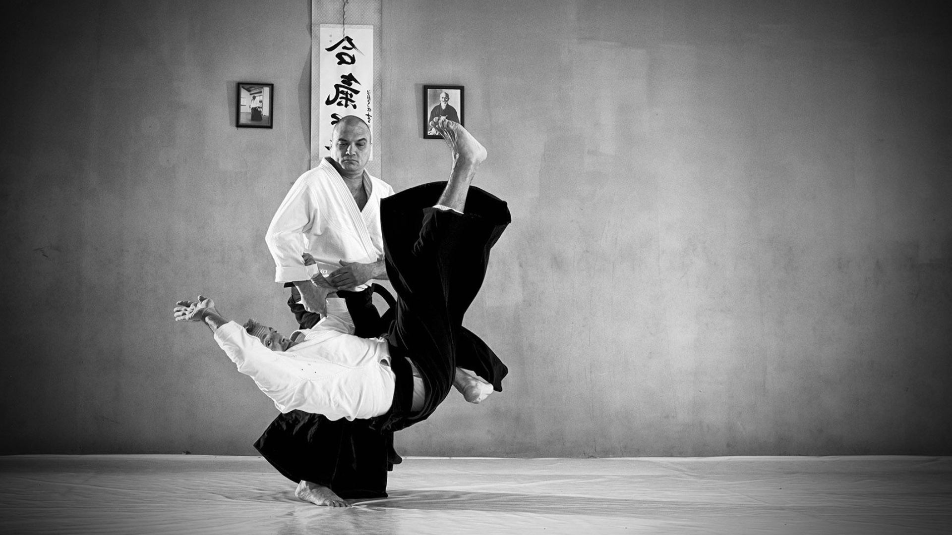 Aikido: Monochrome slanted breath throw technique performed by a tori, Martial arts Sensei. 1920x1080 Full HD Background.
