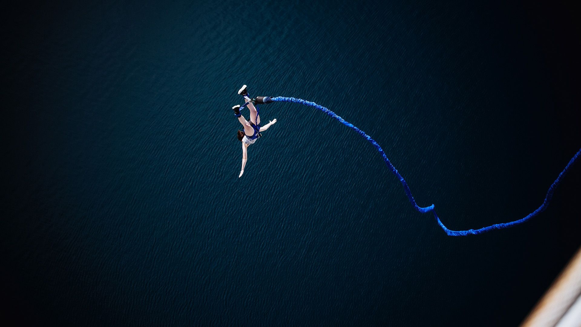 Bungee Jumping: An adrenaline lover connected to a blue ultra-durable elastic rope falls from a helicopter. 1920x1080 Full HD Wallpaper.