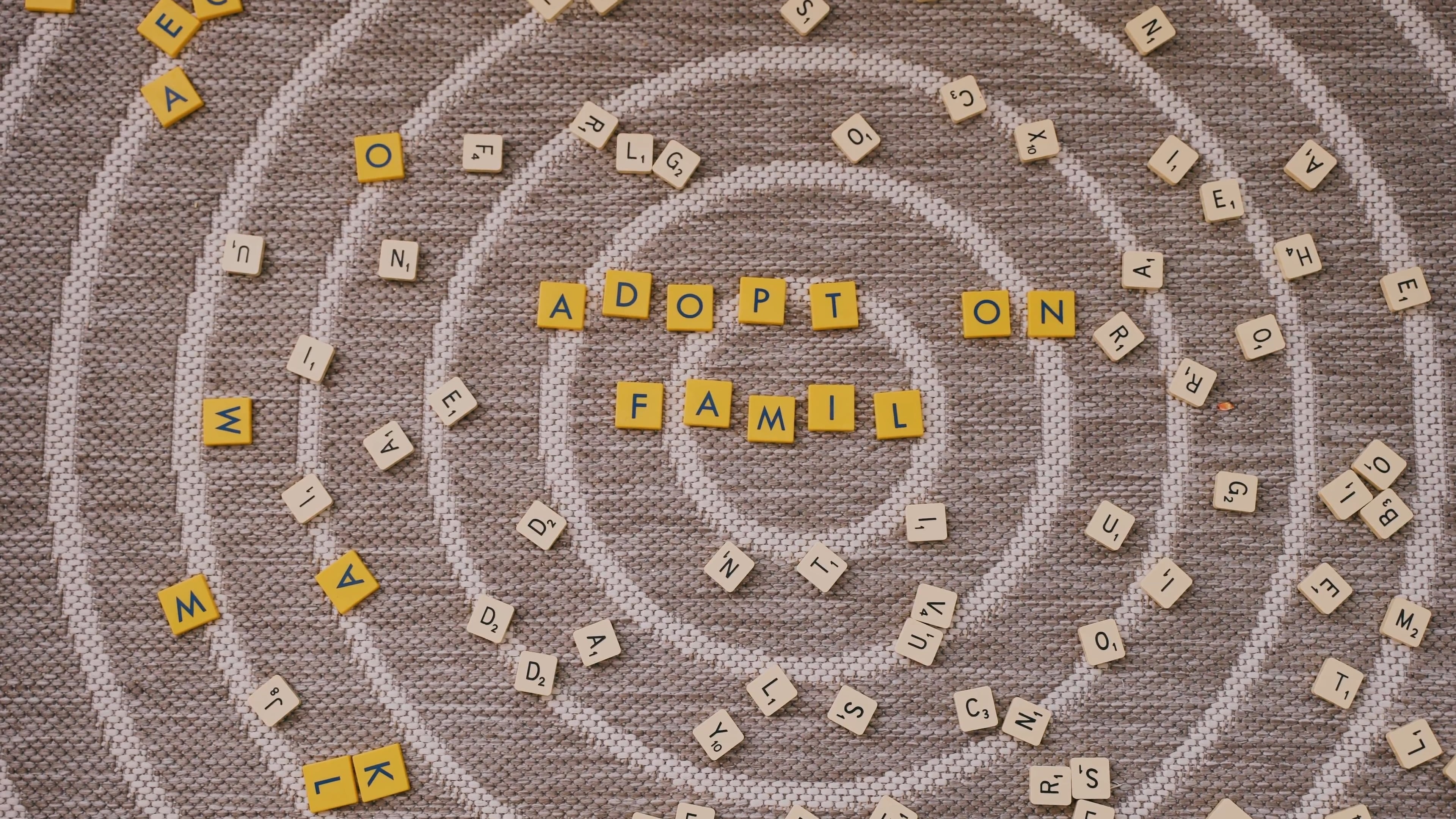 Scrabble: White and yellow letter tiles on the brown carpet, Equipment for a family game. 3840x2160 4K Background.