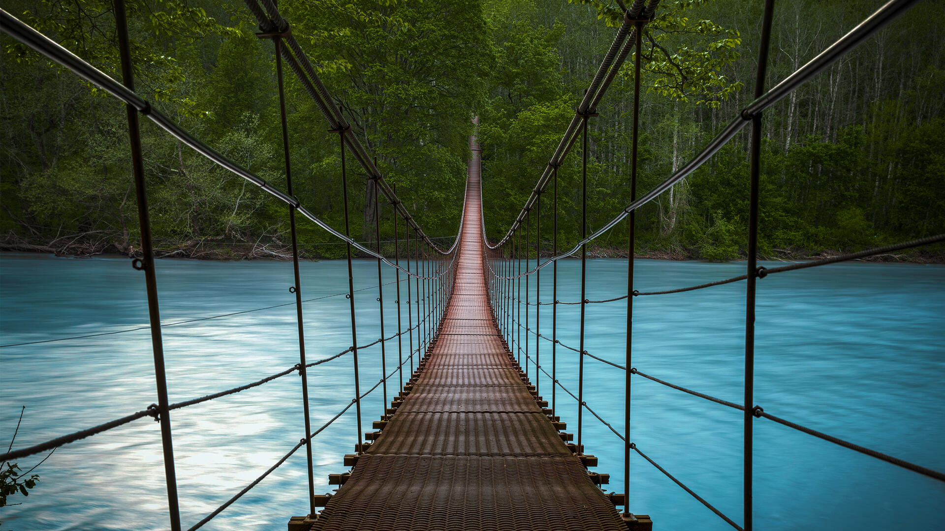 Bridge: A long suspension rope walkway across an amazing blue-water river in the forest. 1920x1080 Full HD Background.
