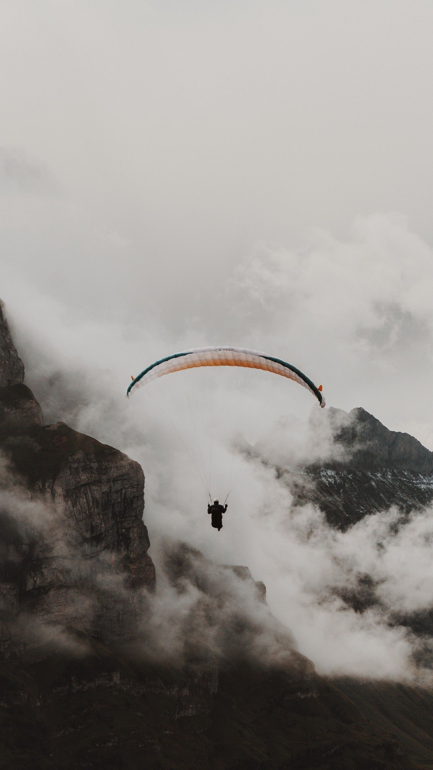 Paragliding: Paraglider Parachute Flying in the cloudy mountains, Altitudes of a few thousand meters. 1440x2560 HD Wallpaper.
