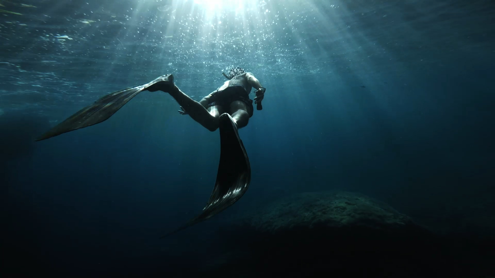 Freediving: A diver equipped with flippers explores the depths of a sea. 1920x1080 Full HD Wallpaper.