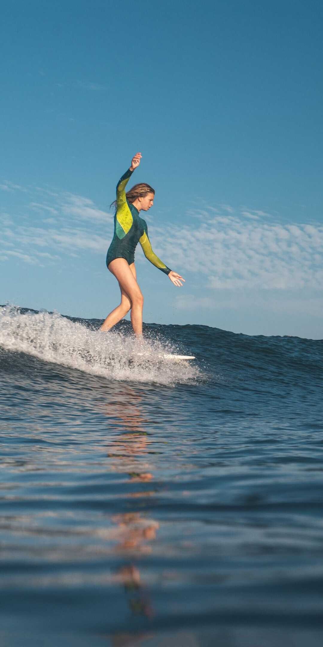 Girl Surfing: Short boarding woman athlete, Riding a surfboard, Recreational water sports. 1080x2160 HD Background.