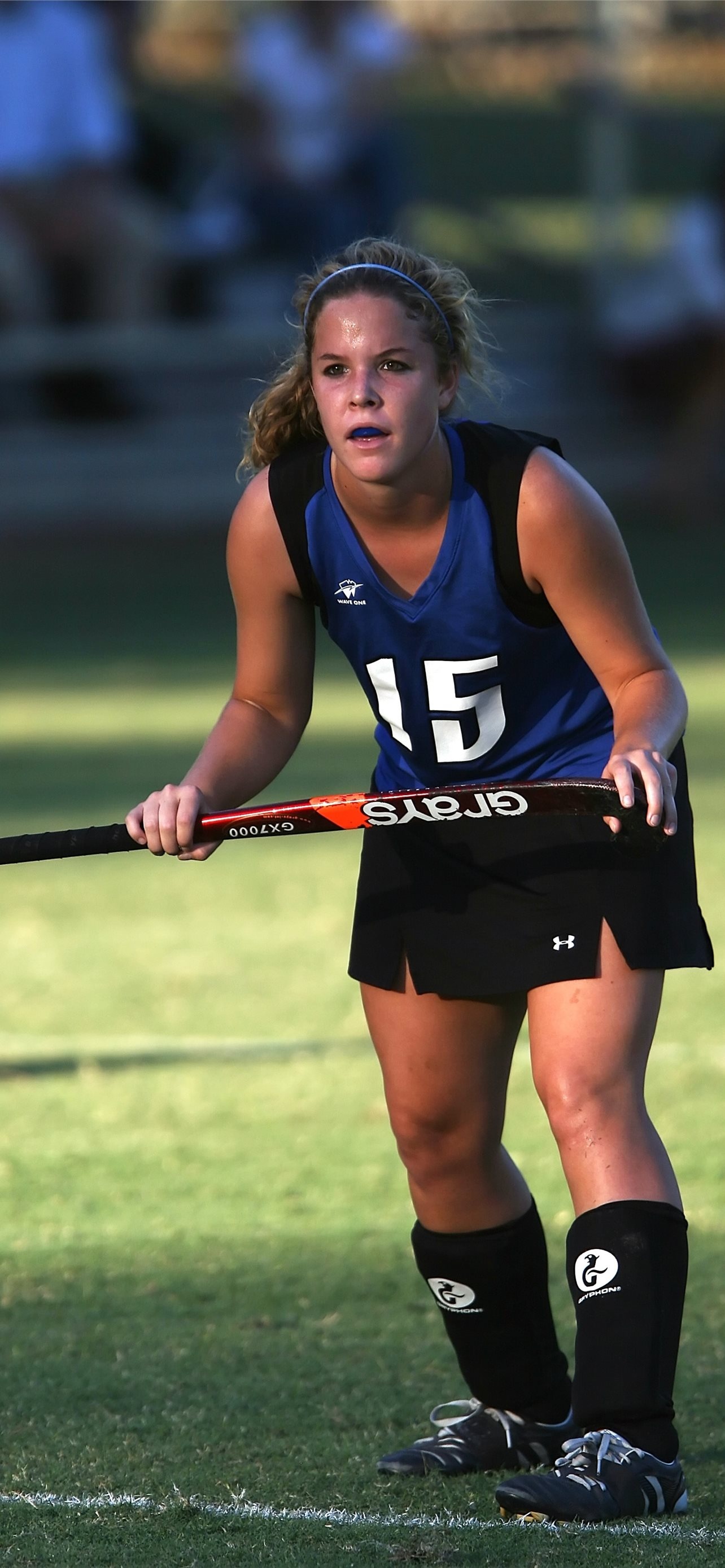 Field Hockey: A female player equipped with a stick, Outdoor competitive sport. 1290x2780 HD Background.