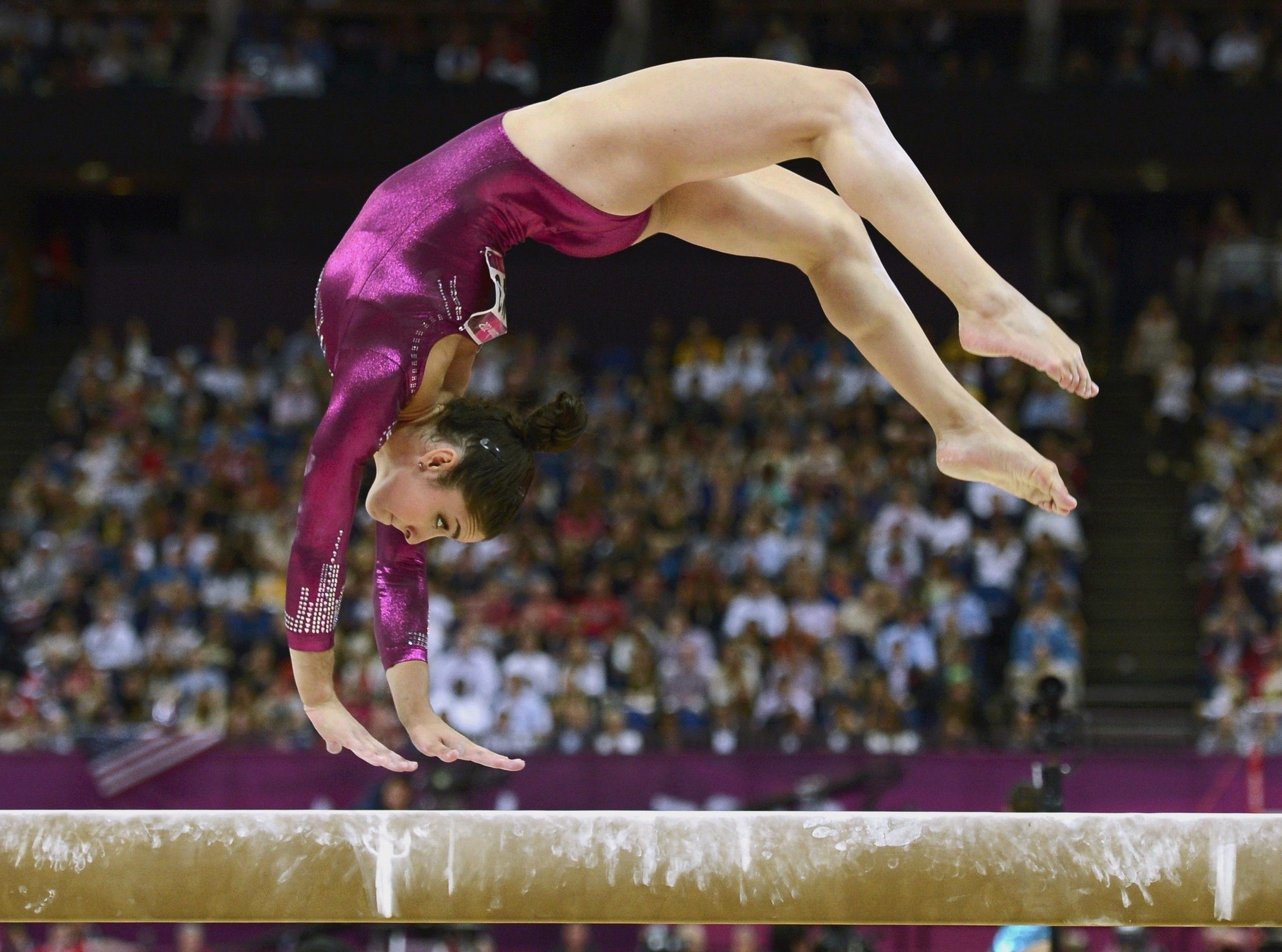 Balance Beam: A girl performing a back flip during a gymnastics competition event. 2560x1910 HD Background.