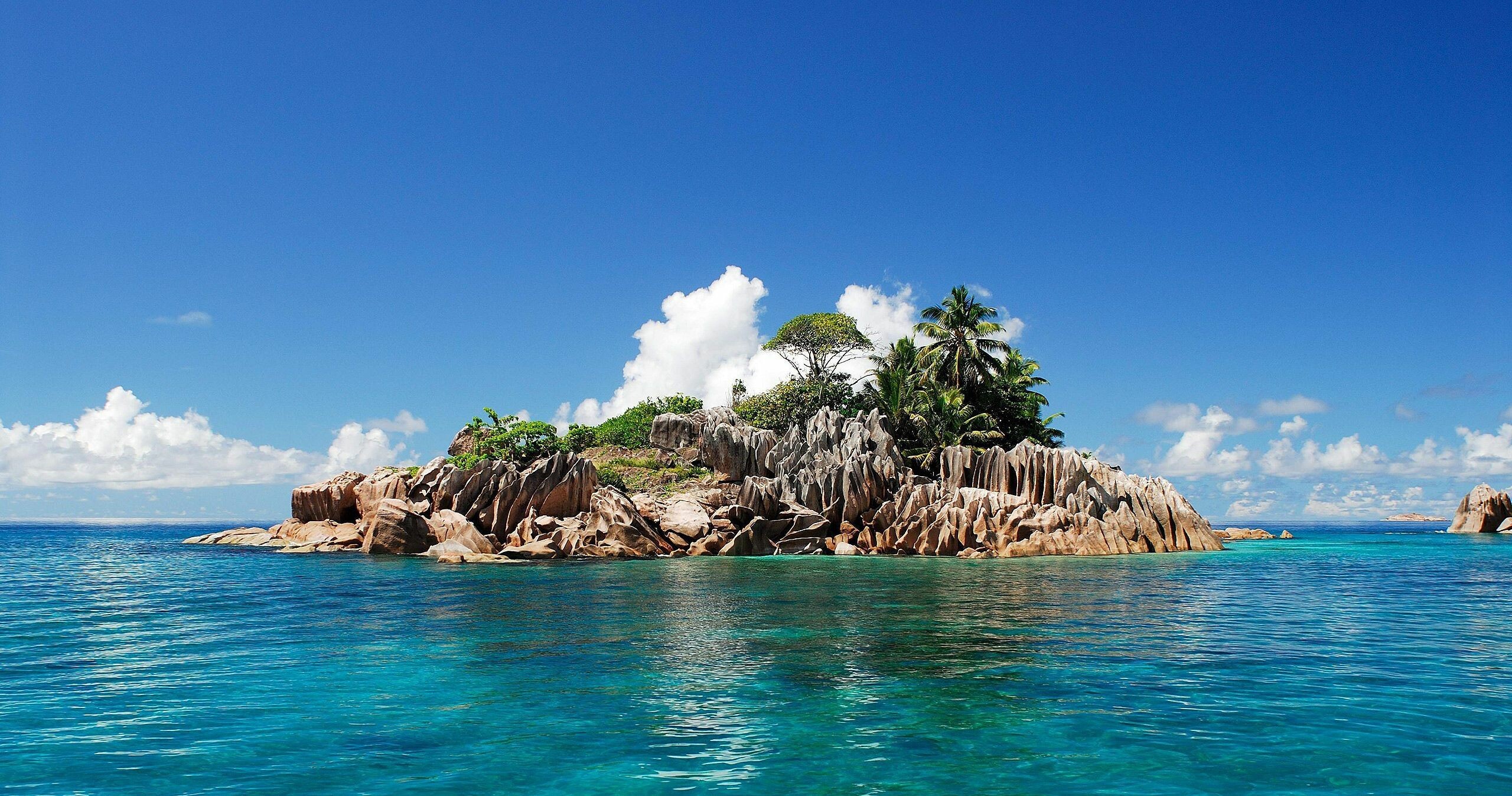 Island: A rocky reef, Known as a low sea stack, Ocean. 2560x1350 HD Wallpaper.