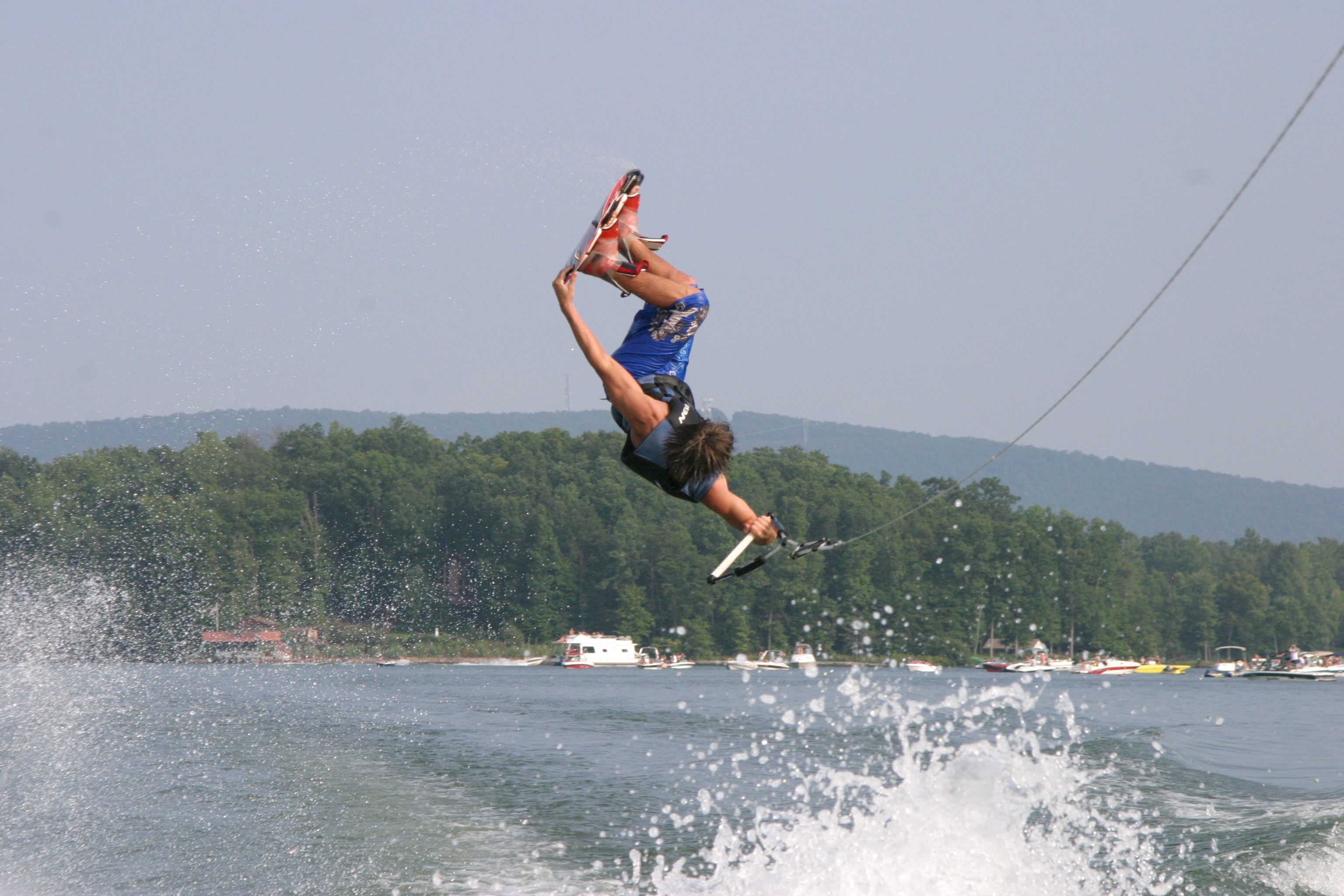 Wakeboarding: Riding a surfboard towed behind a motorboat, Backflip in the air by a stuntman. 3080x2050 HD Background.
