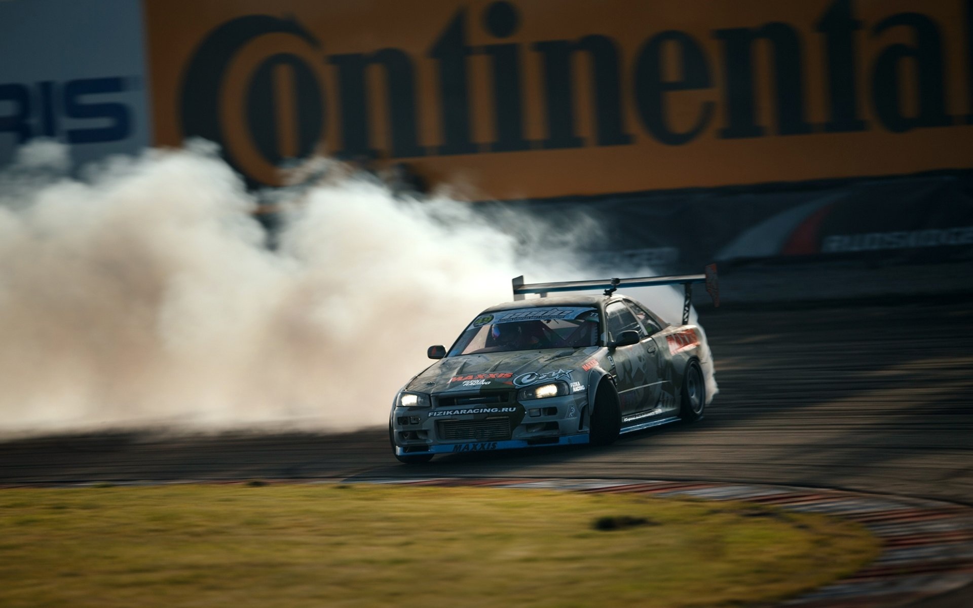 Drifting: Oversteered Nissan Skyline, Smoking Maxxis tires, Motorsports competition. 1920x1200 HD Background.