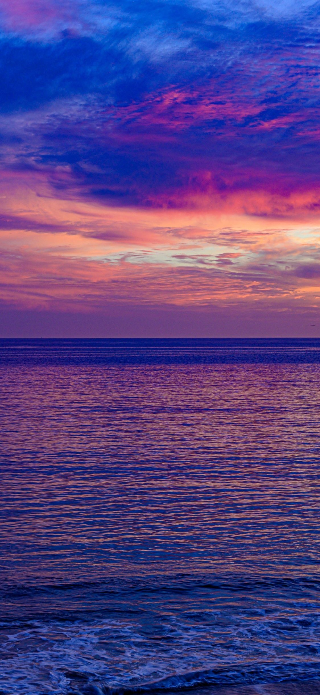 Seascape: The still water surface in the late sunset time, Perfect horizon line, Incredible view. 1130x2440 HD Background.