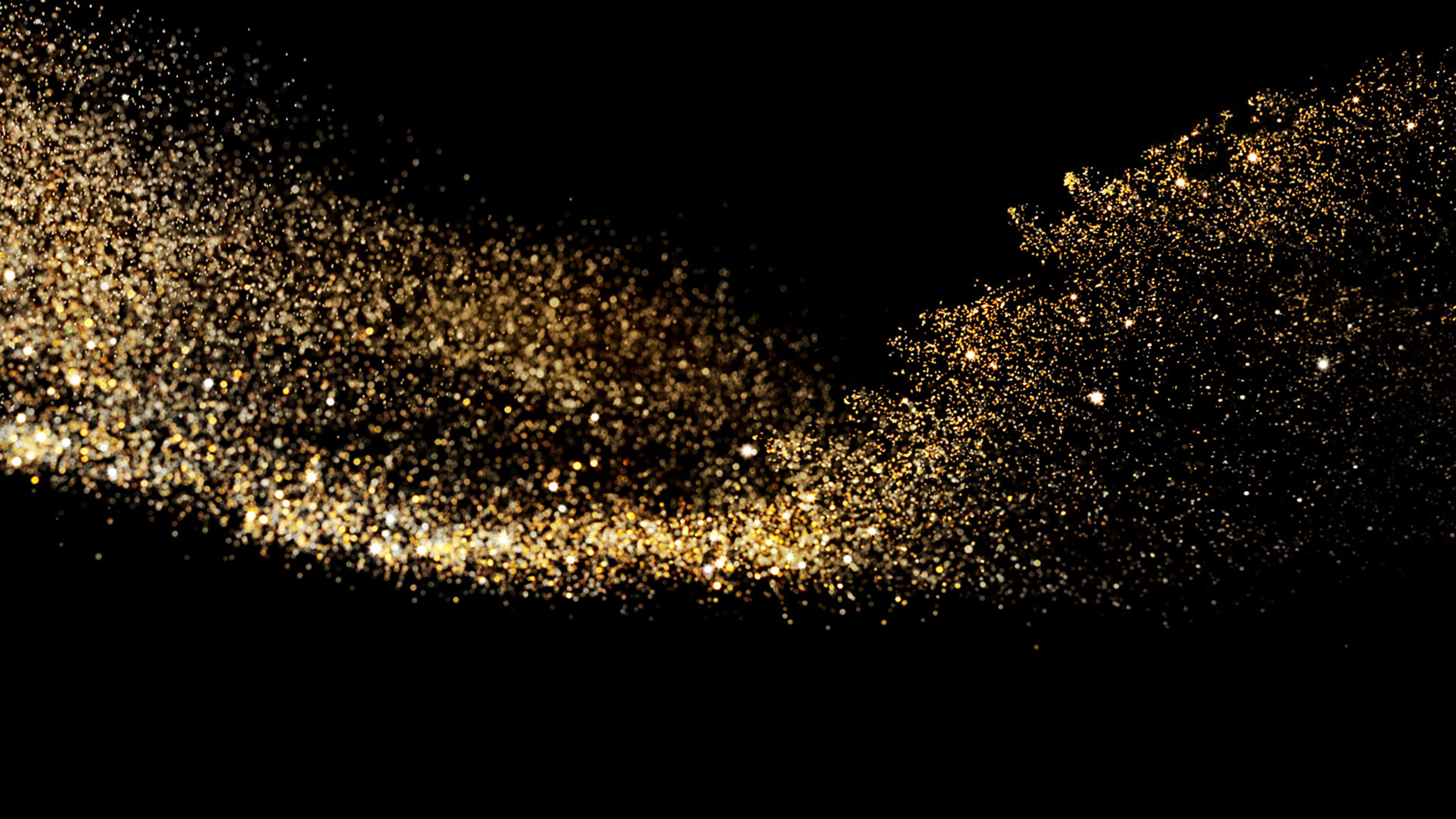 Gold Sparkle: Small particles with golden glittering surfaces scattered in the darkness, Golden dust explosion. 3840x2160 4K Background.
