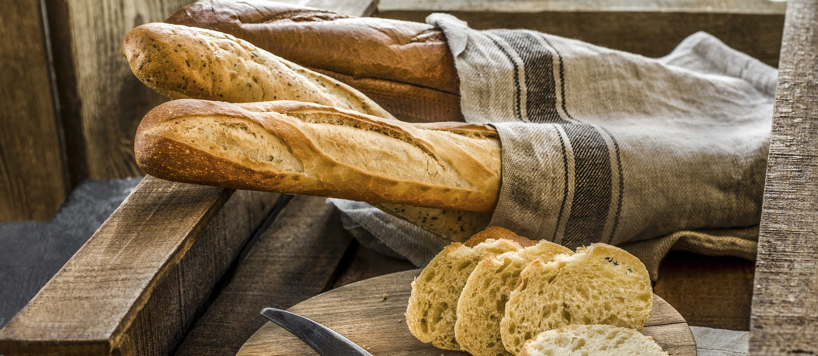 Baguette: A long, thin loaf of bread with a crisp crust and soft interior. 2800x1220 Dual Screen Background.