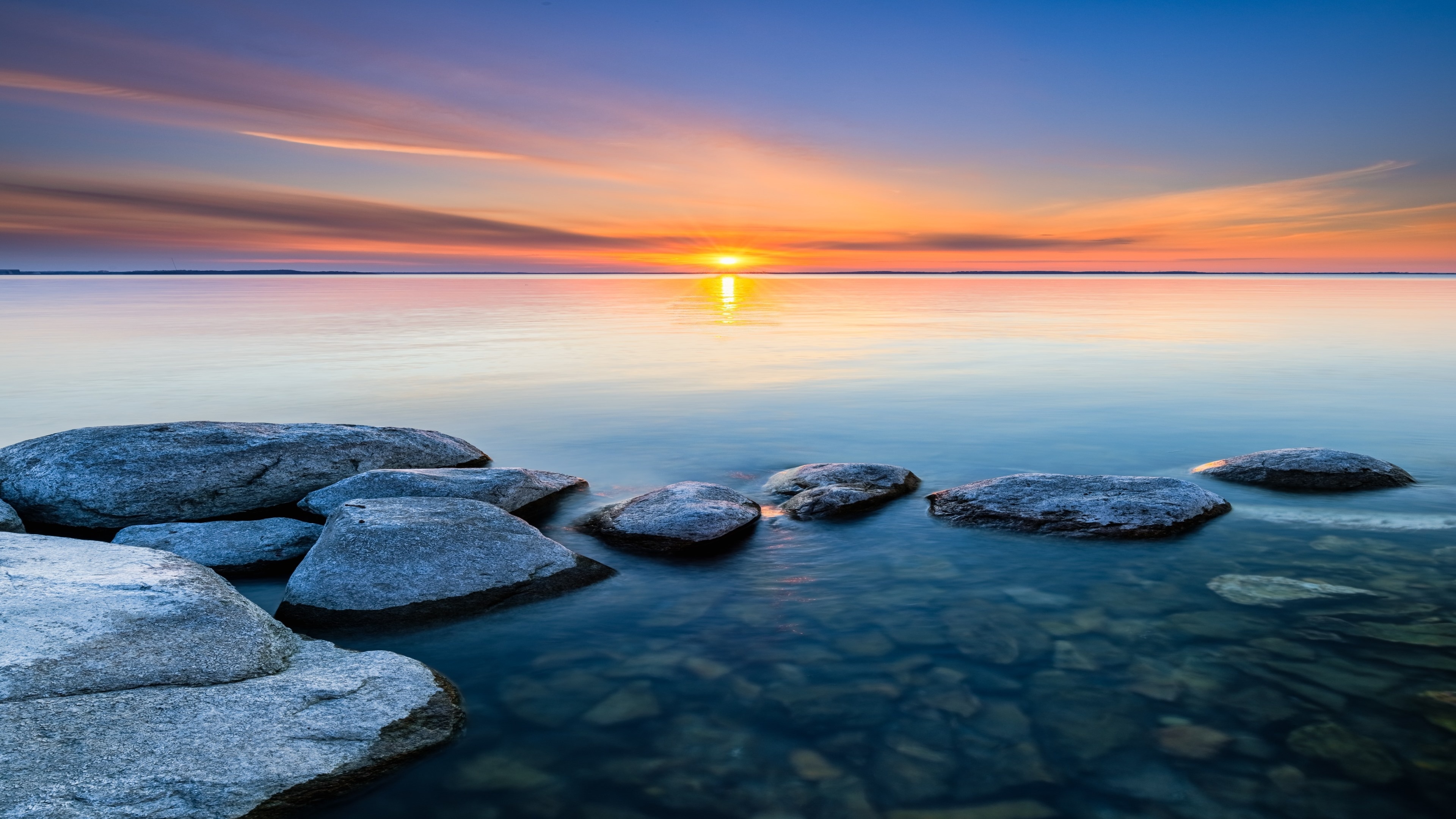 Seascape: The rare still water moment at the rocky coast of the sea, Sunset time. 3840x2160 4K Background.
