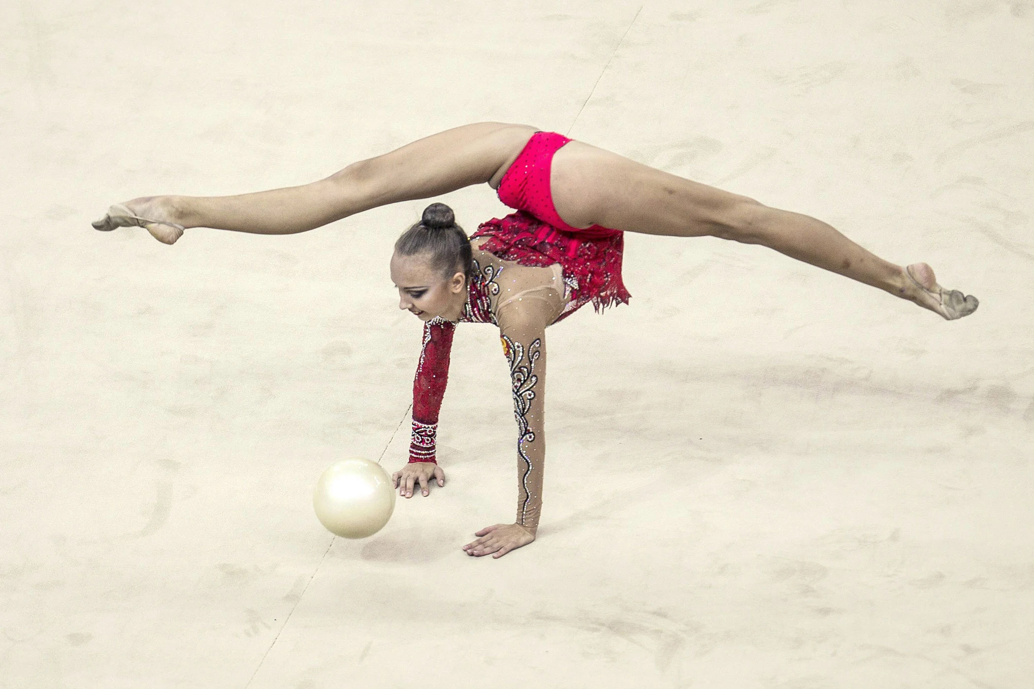 Rhythmic Gymnastics: An artistic exercise with a special ball, Sports choreography performed by a female gymnast. 2100x1400 HD Background.